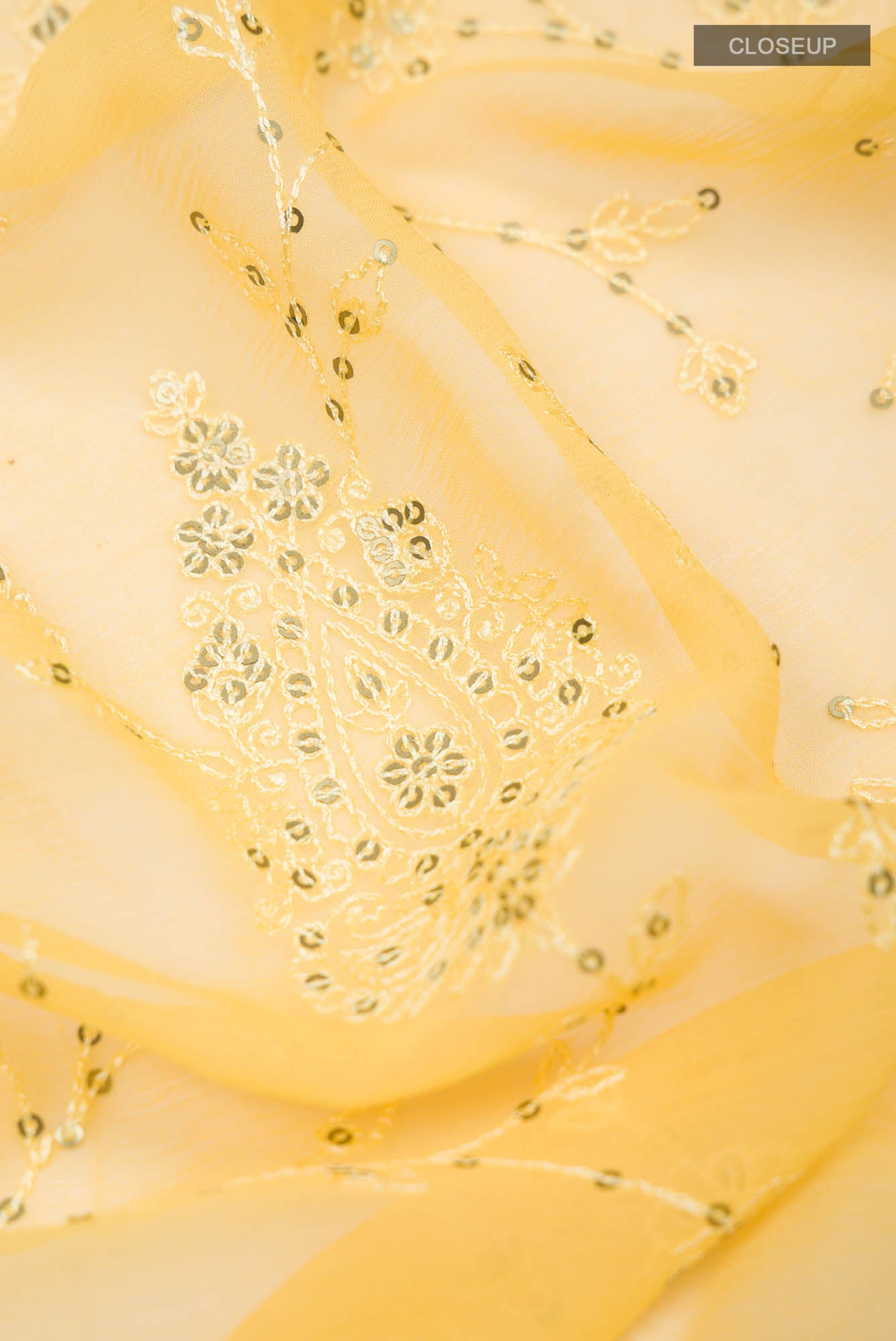 Close up of Yellow Blended Chiffon Saree with Embroidery on the body and Lace Border.  displaying folds
