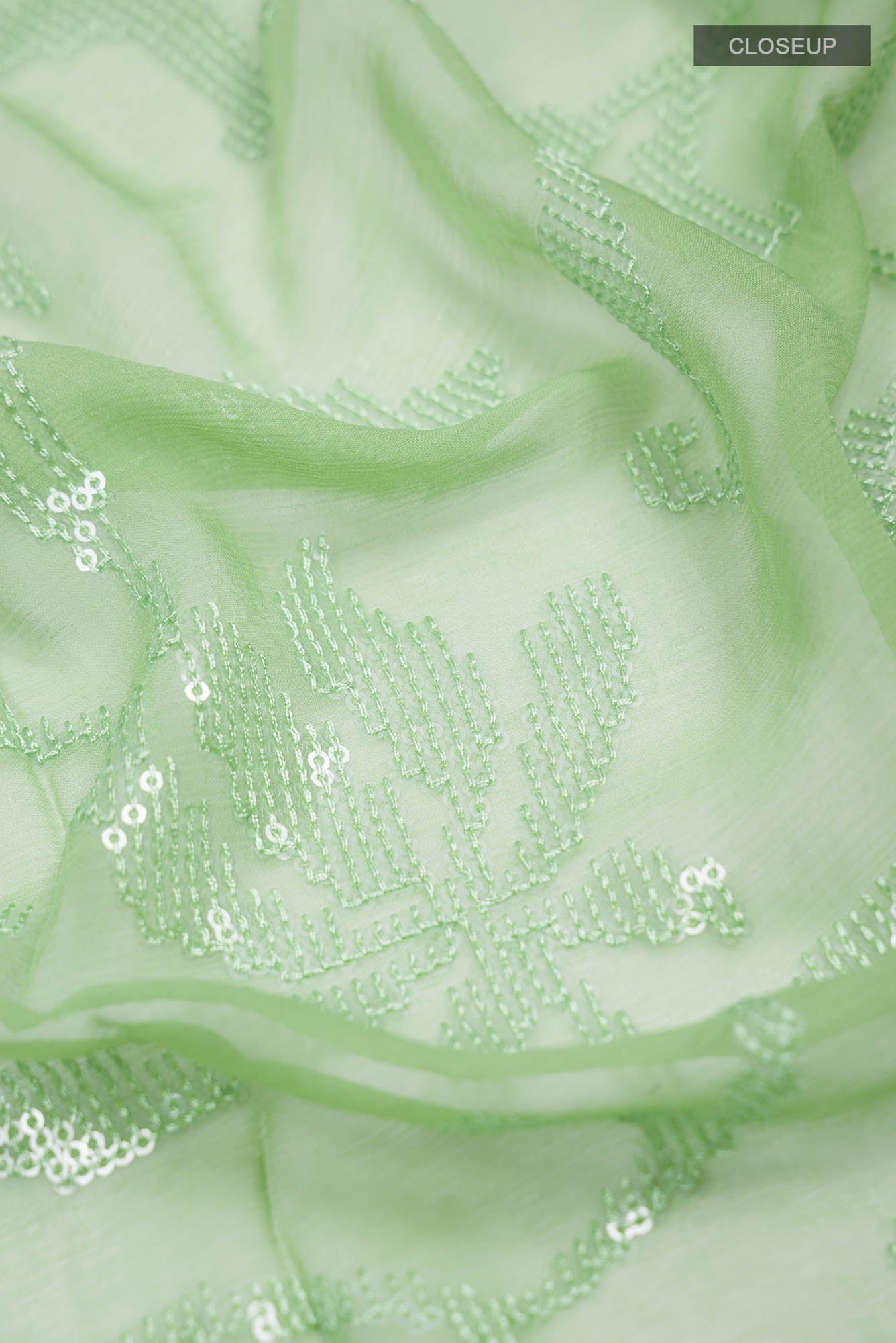 Close up of Green Blended Chiffon Saree with Embroidery on the body and Lace Border.  displaying folds