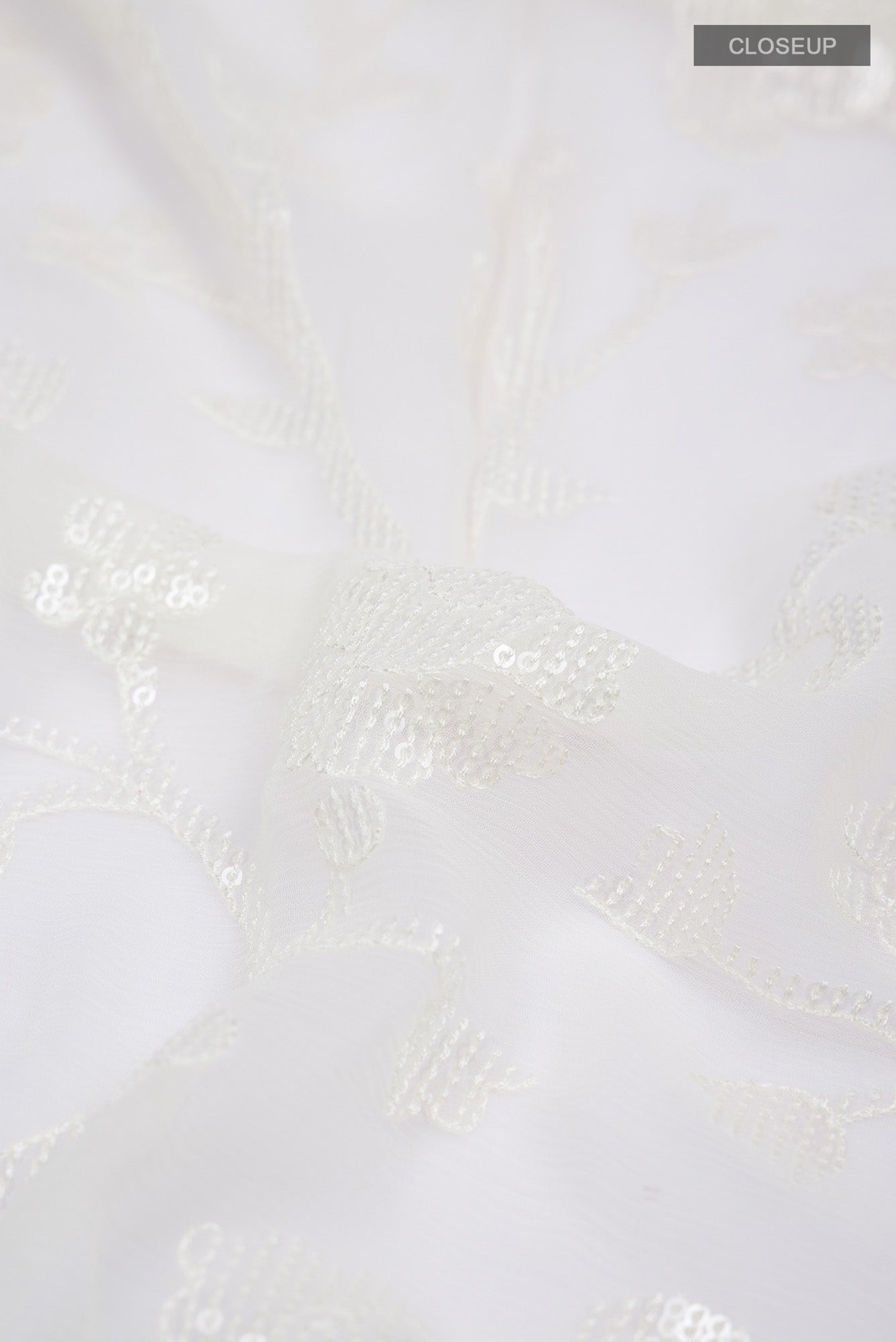 Close up of Cream Blended Chiffon Saree with Embroidery on the body and Lace Border.  displaying folds