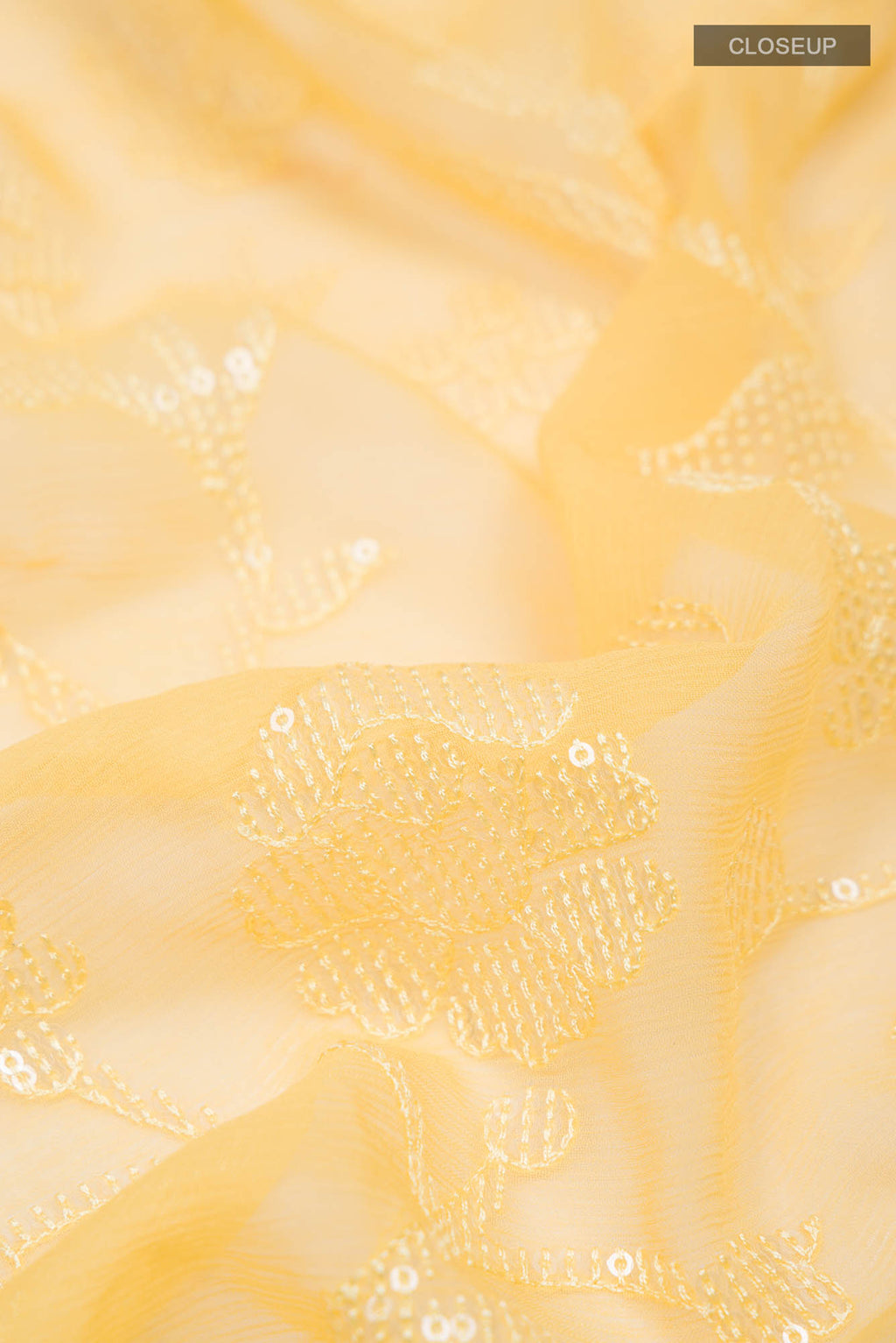 Close up of Yellow Blended Chiffon Saree with Embroidery on the body and Lace Border.  displaying folds