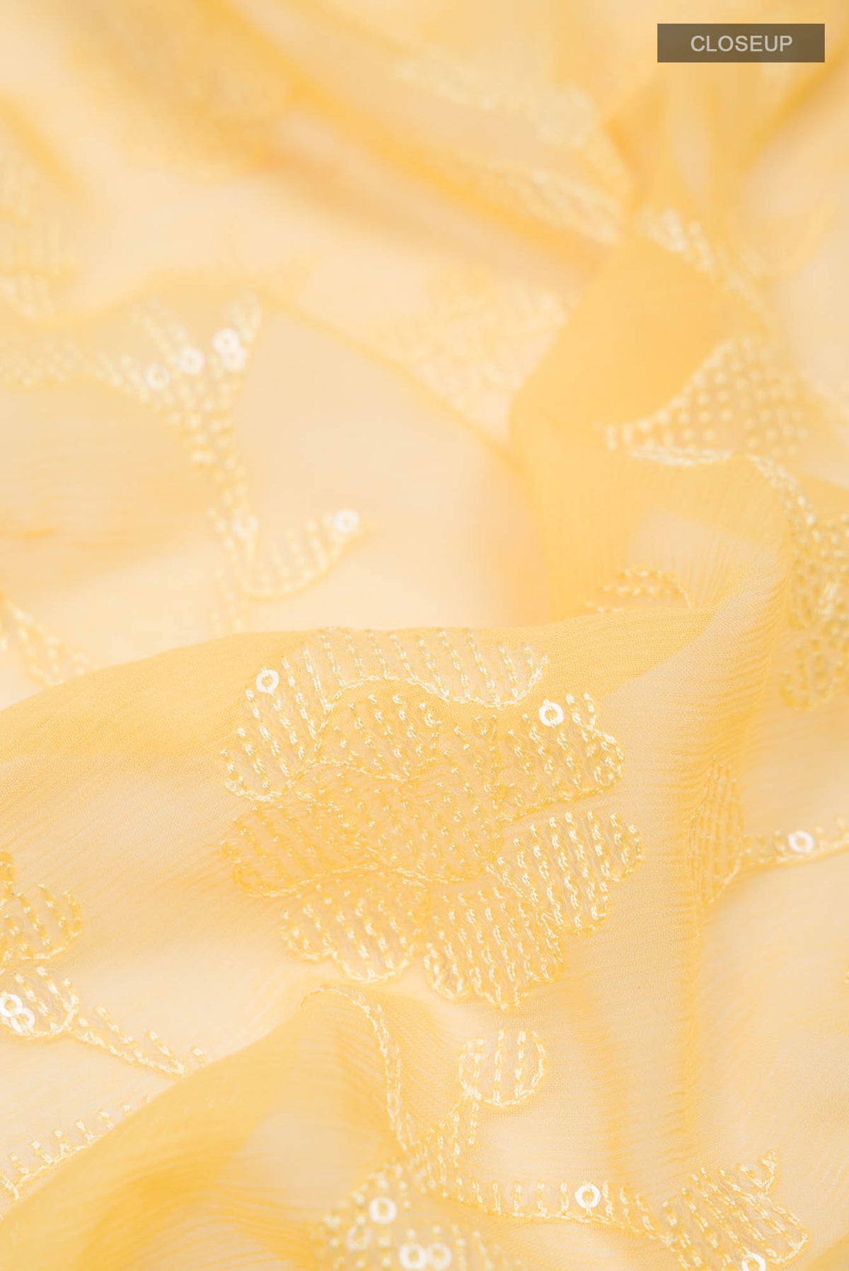 Close up of Yellow Blended Chiffon Saree with Embroidery on the body and Lace Border.  displaying folds