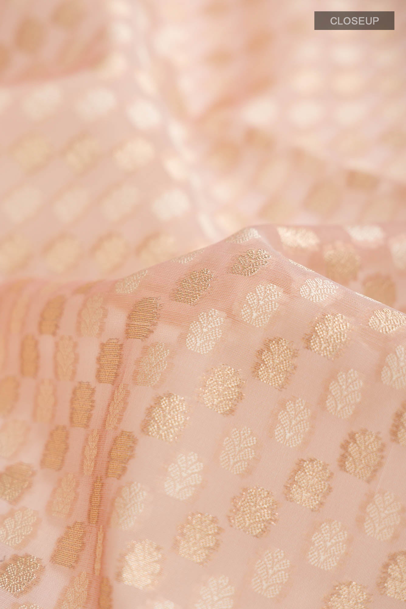 Close up of Rose Gold Blended Kora Cotton Saree with Zari And Thread Butta on the body and Zari Border.  displaying folds