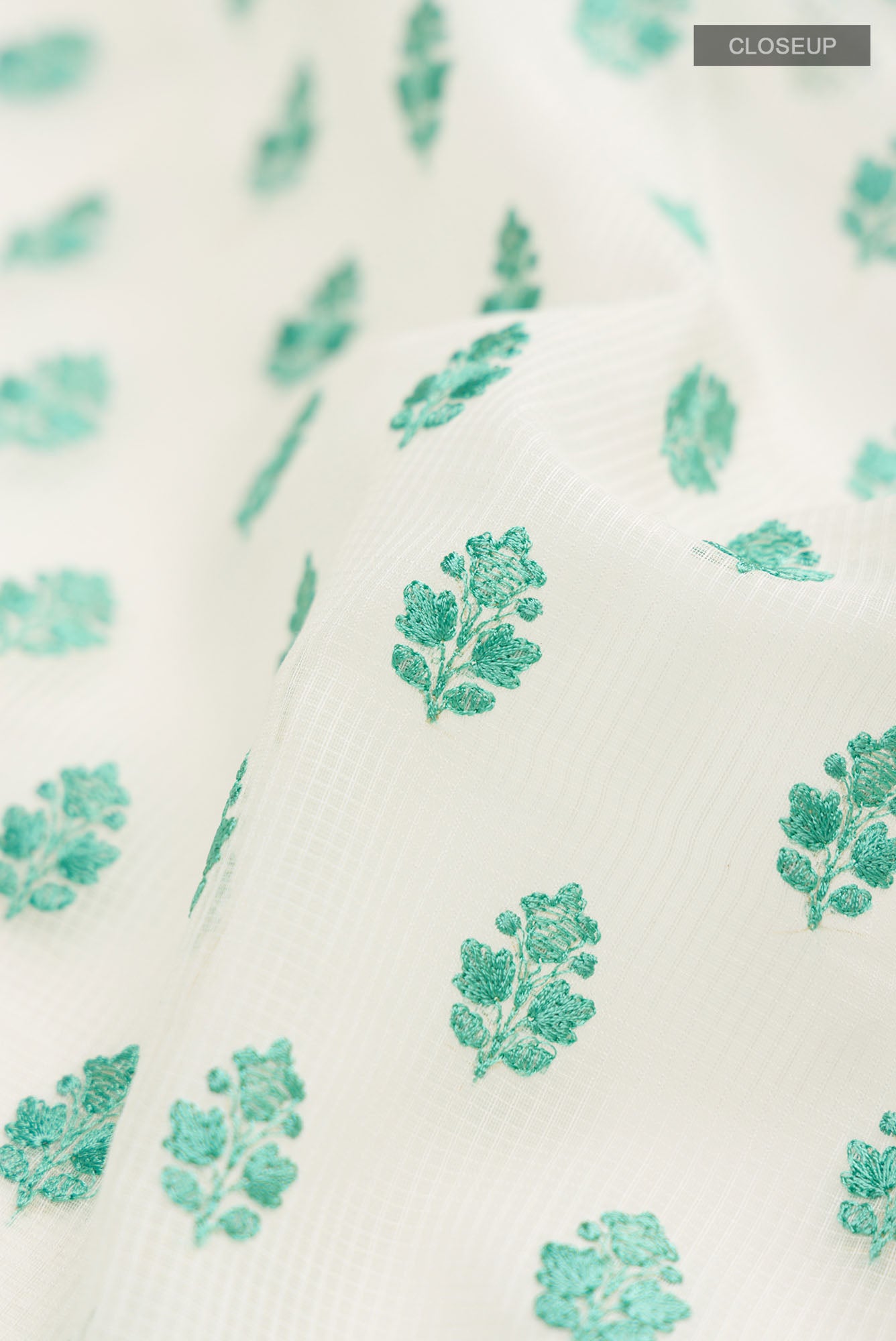 Close up of Cream Blended Kota Cotton Saree with Embroidery on the body and Thread Border.  displaying folds