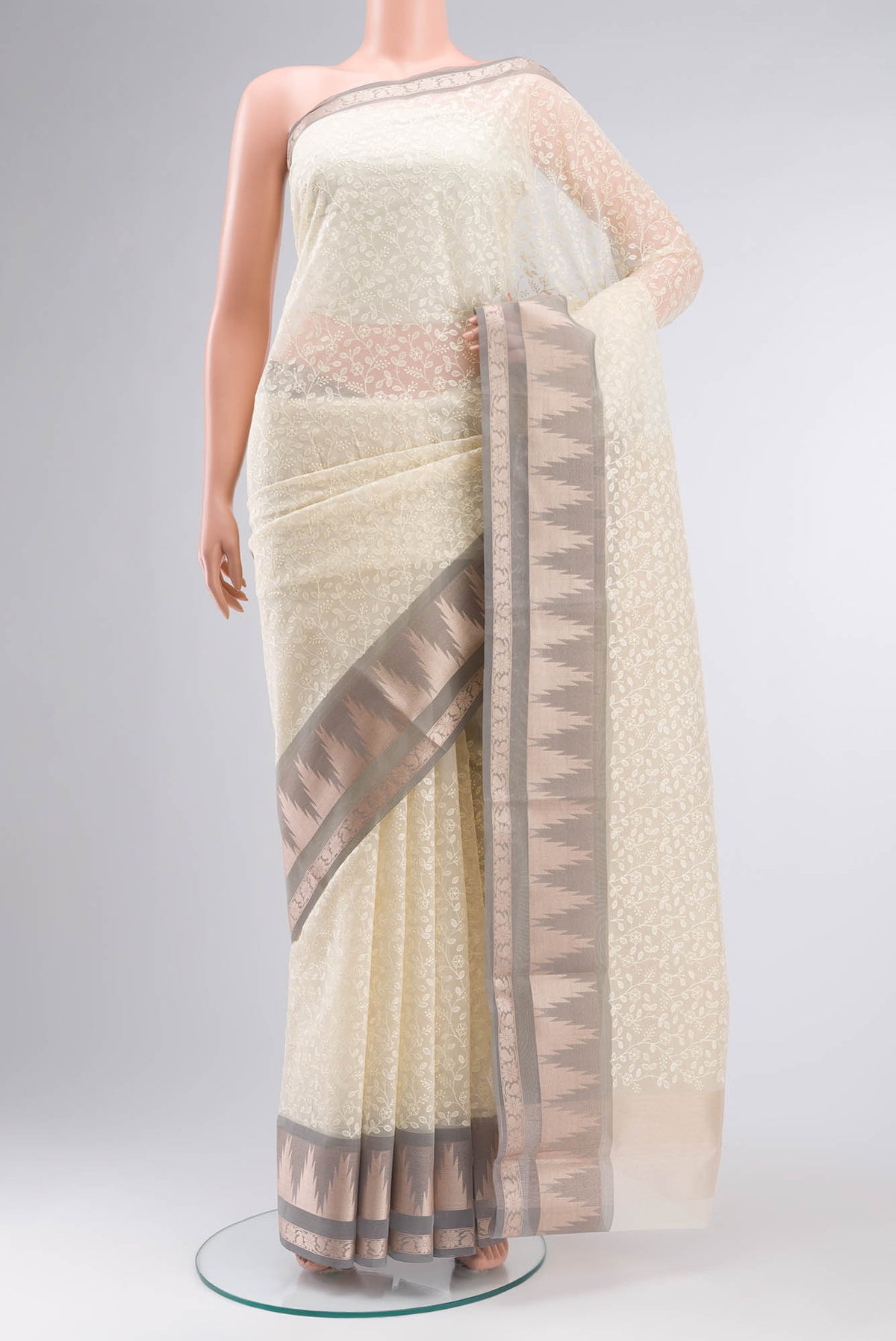 Cream Blended Kora Cotton Saree with Embroidery on the body and Zari And Thread Border.  displayed on a mannequin