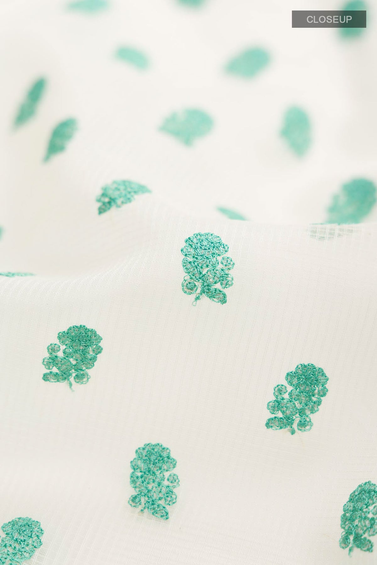 Close up of Cream Blended Kota Cotton Saree with Embroidery on the body and Thread Border.  displaying folds