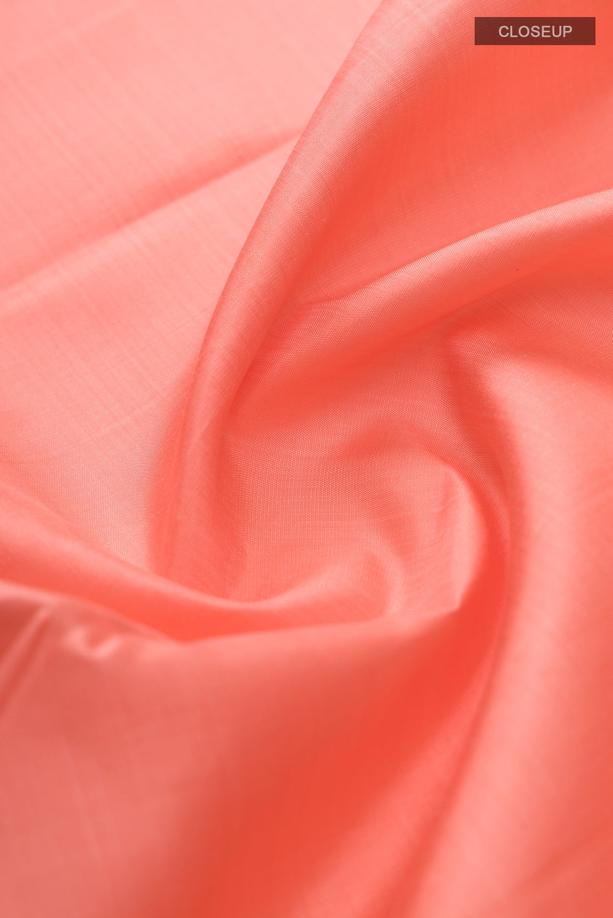 Close up of Peach Kanjivaram Silk Saree with Plain Body and Zari Border.  displaying folds
