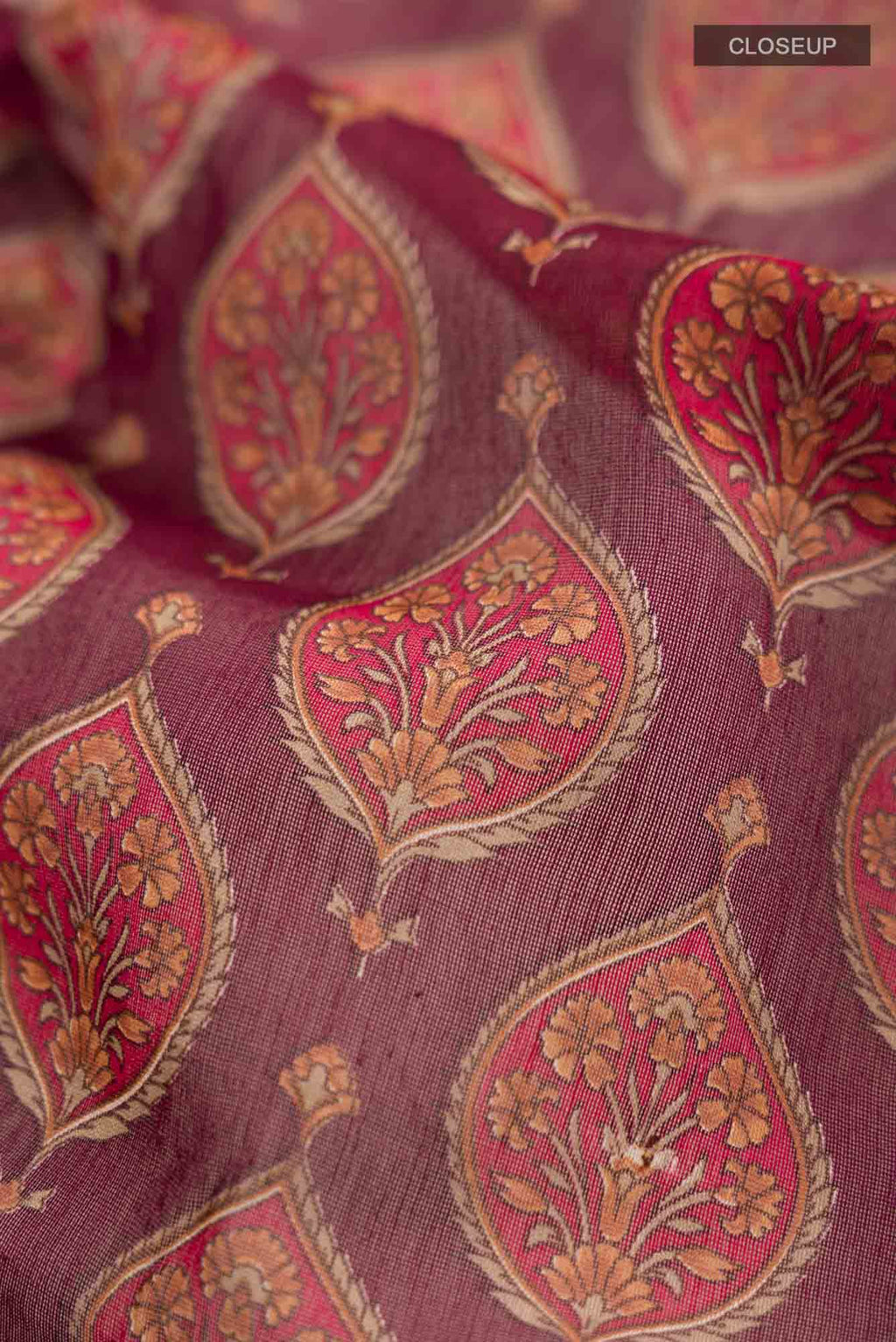 Close up of Maroon Silk Cotton Saree with Floral Print on the body and Zari Border.  displaying folds