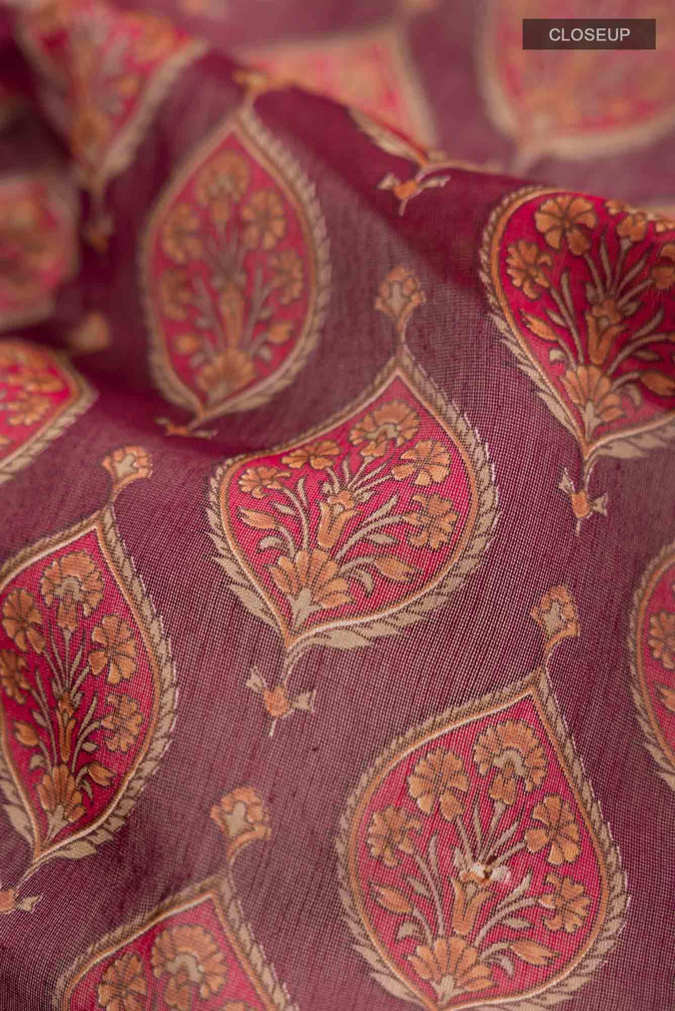 Close up of Maroon Silk Cotton Saree with Floral Print on the body and Zari Border.  displaying folds