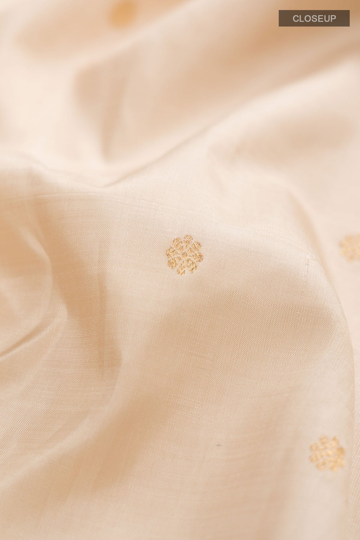Close up of Cream Kanchipuram Silk Saree with Zari Butta on the body and Zari Border displaying folds