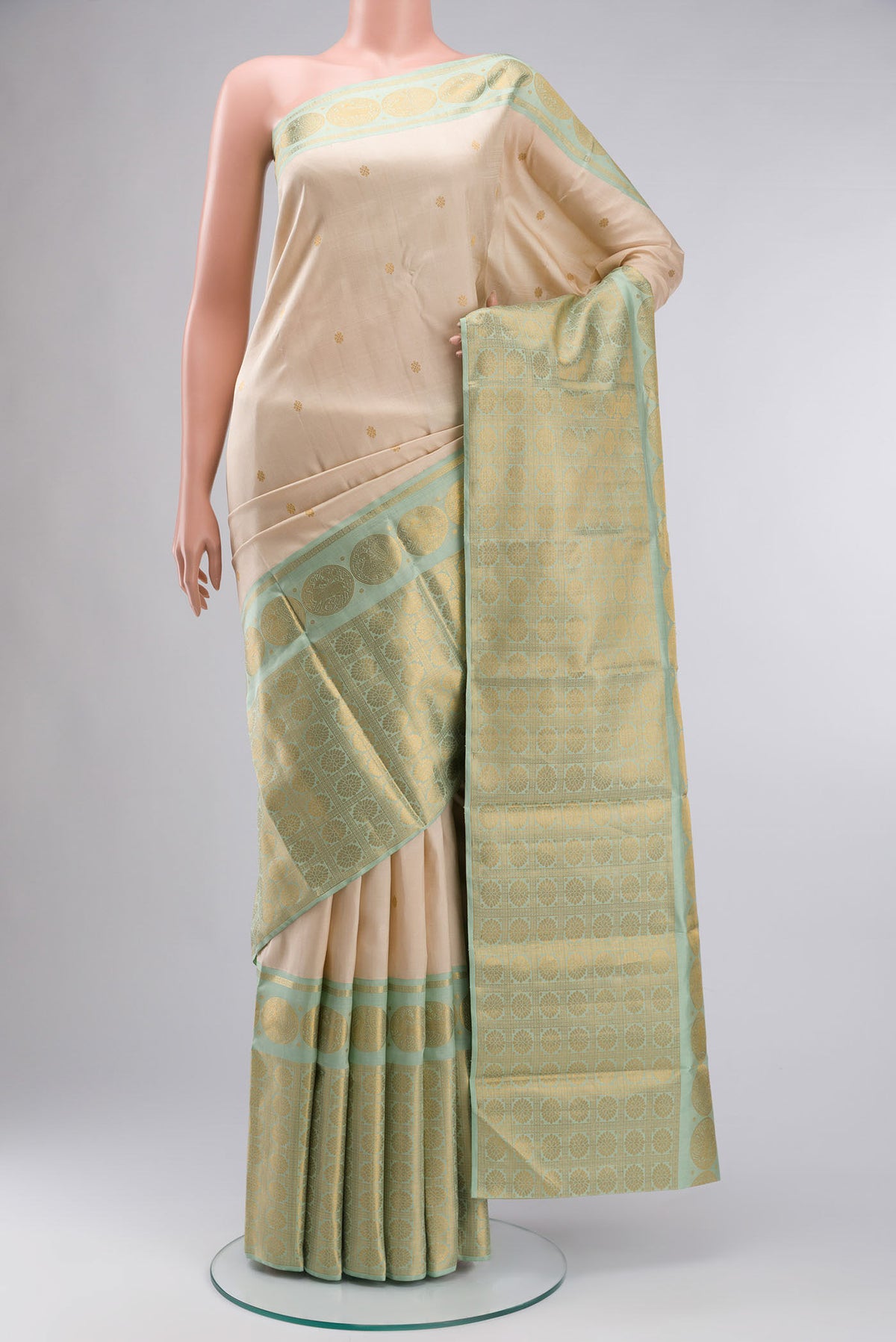 Cream Kanchipuram Silk Saree with Zari Butta on the body and Zari Border displayed on a mannequin