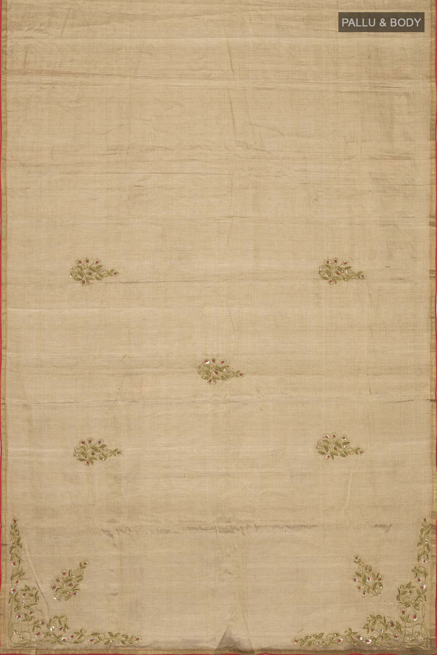 Flat view of Rumana is crafted in delicate tissue enriched with antique-gold zardozi, brought to life through dabka, sequins, and coloured beads The pallu unfolds with konia motifs and flowing pomegranate vines, anchored by a drop-shaped buta rendered in a stylised pomegranate form The body carries evenly placed butas that continue into the pleats, lending the saree a gentle, composed rhythm A classic gota trim completes this elegant expression of symbolic craft