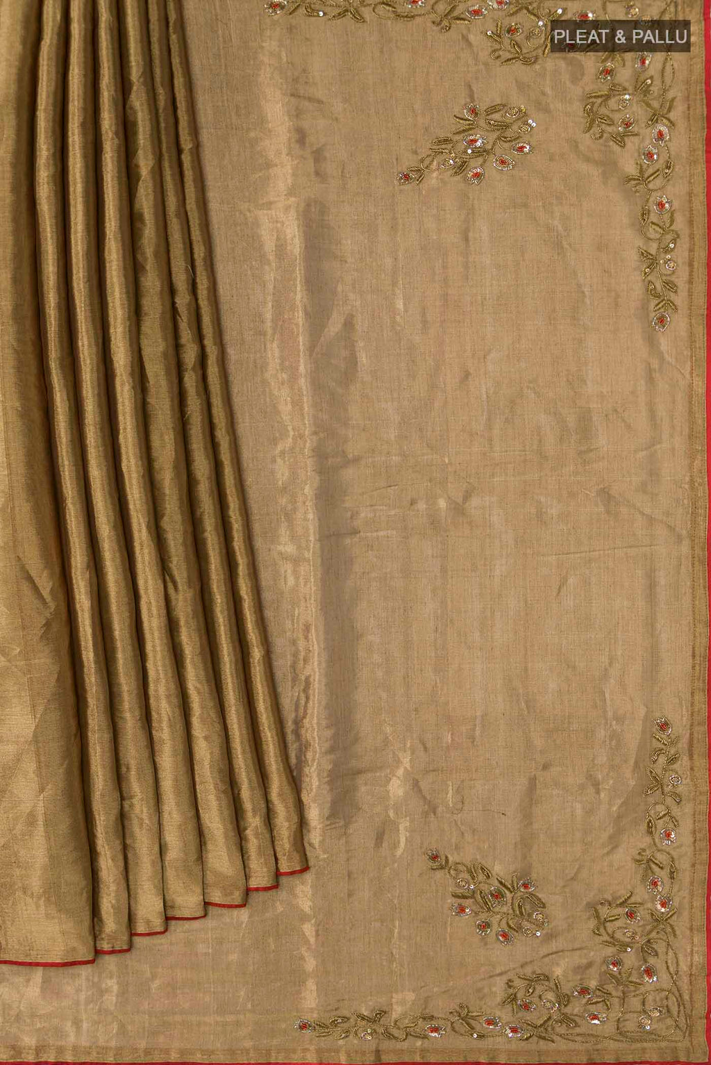 Pleats and pallu of Rumana is crafted in delicate tissue enriched with antique-gold zardozi, brought to life through dabka, sequins, and coloured beads The pallu unfolds with konia motifs and flowing pomegranate vines, anchored by a drop-shaped buta rendered in a stylised pomegranate form The body carries evenly placed butas that continue into the pleats, lending the saree a gentle, composed rhythm A classic gota trim completes this elegant expression of symbolic craft