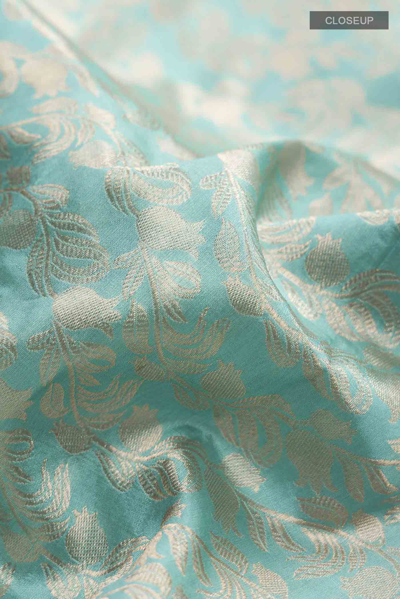 Close up of Turquoise Banarasi Katan Silk Saree with Zari Butta on the body and Zari Border displaying folds