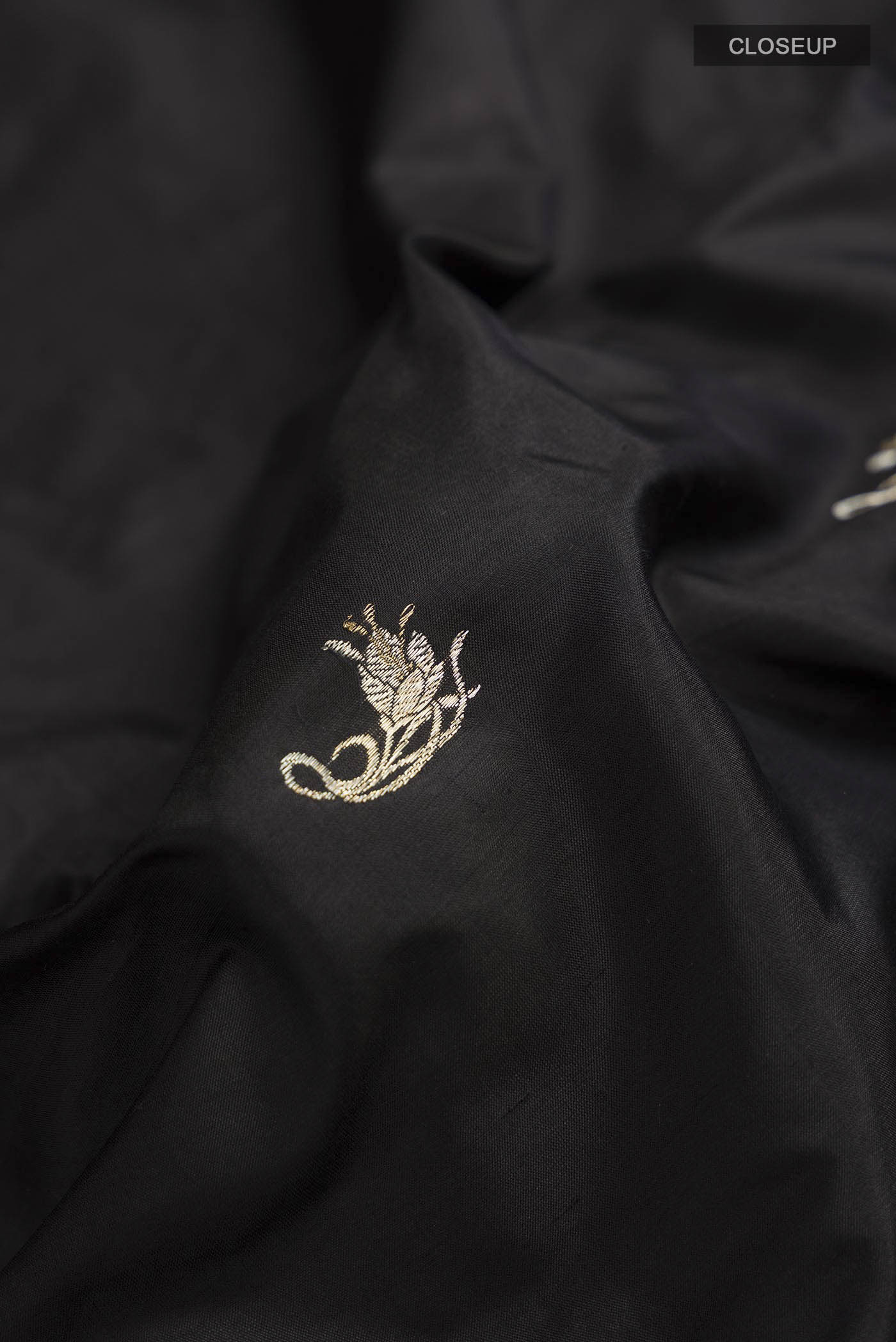 Close up of Black Banarasi Katan Silk Saree with Zari Butta on the body and Zari Border displaying folds