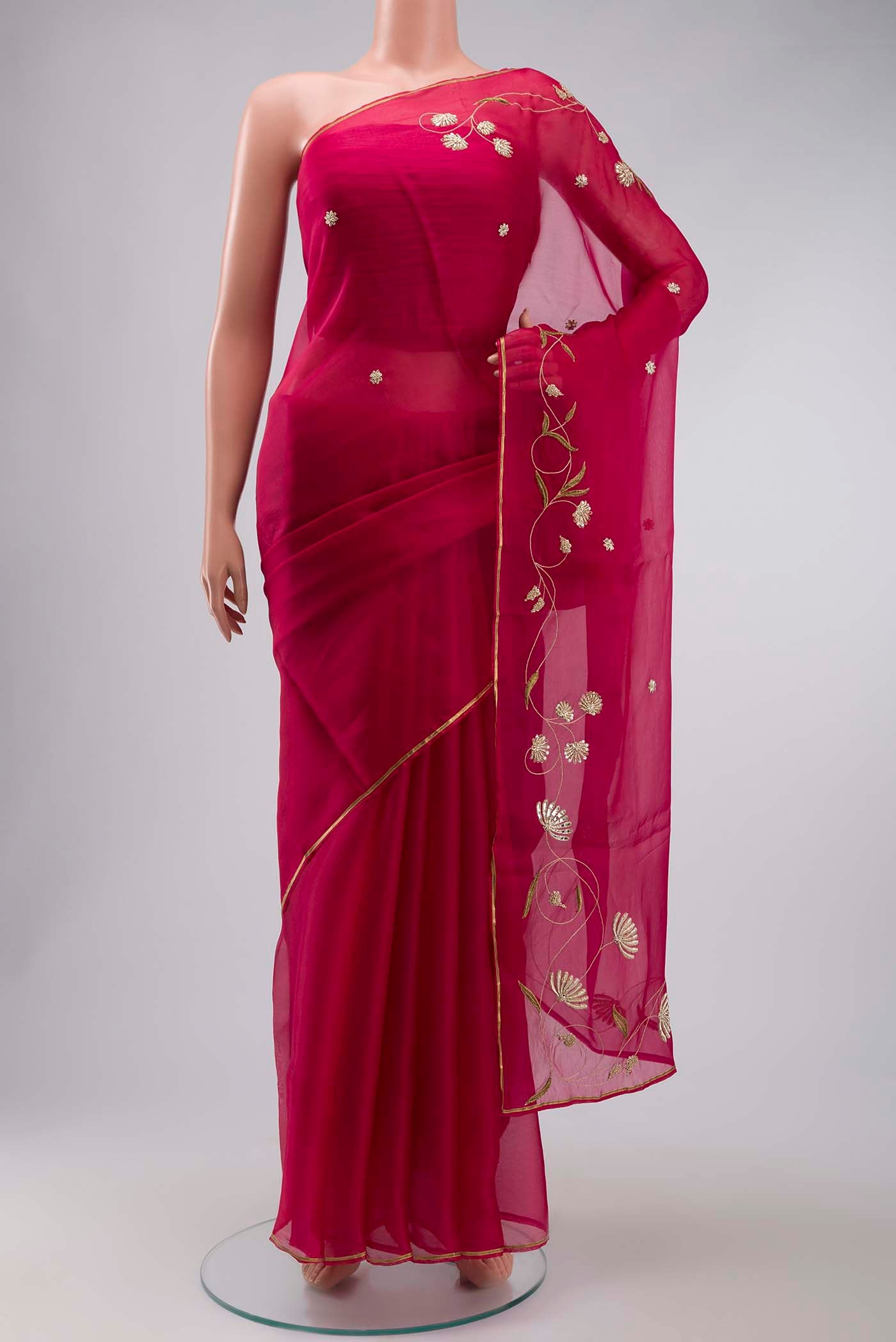 Bahar, crafted in silk organza, features delicate pani-zari enriched with zardozi, gota work, and dabka embroidery Its defining element is an off-center floral vine running vertically through the body, breaking symmetry with quiet intent Inspired by Art Nouveau?s flowing lines, the vine is rendered in slender leaves, zari chain-stitched stems, and alternating gota and zardozi flowers The pallu trails gently onto the body in scattered embroidered blooms displayed on a mannequin