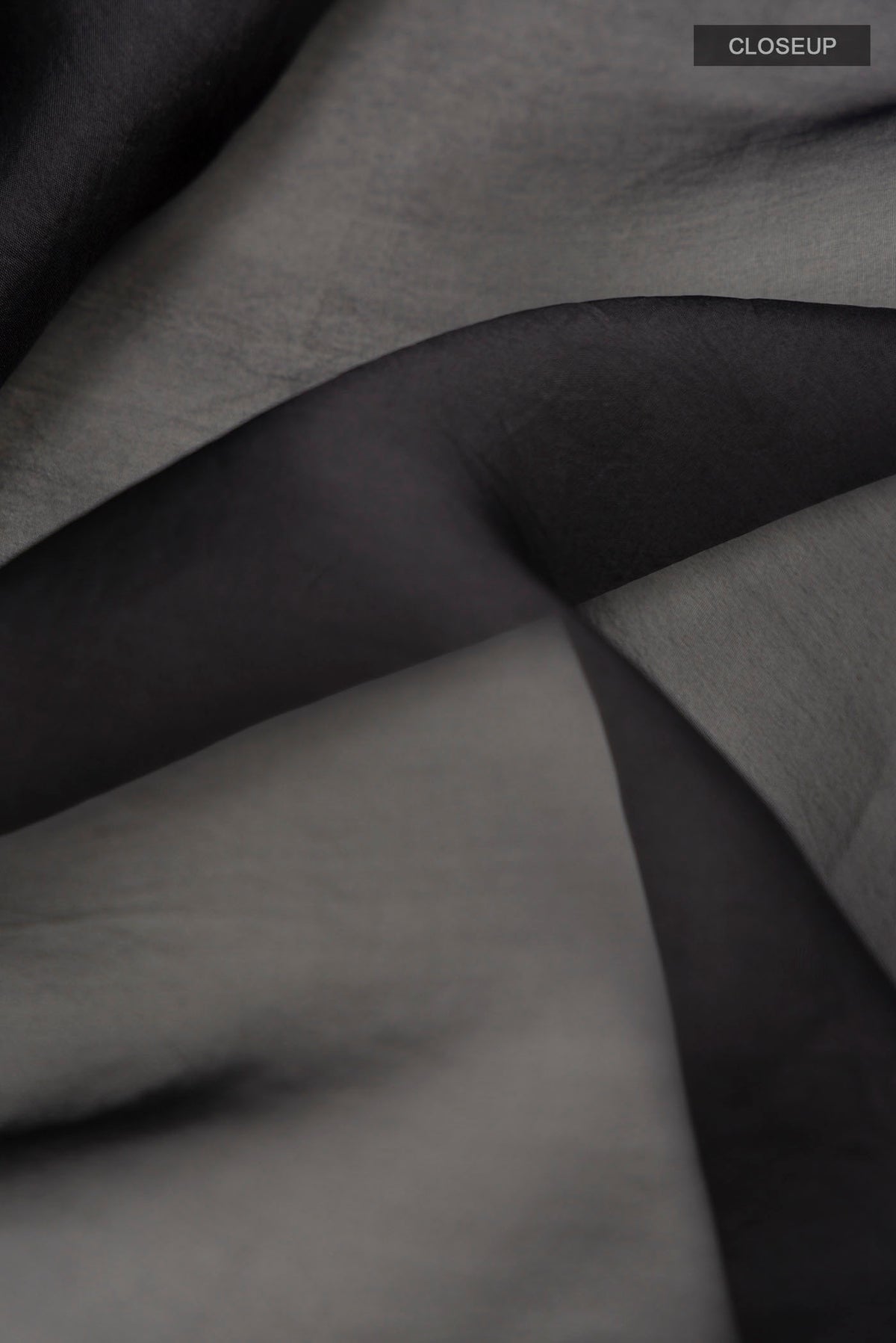 Close up of Black Organza Silk Saree with Plain Body and Embroidery Border displaying folds
