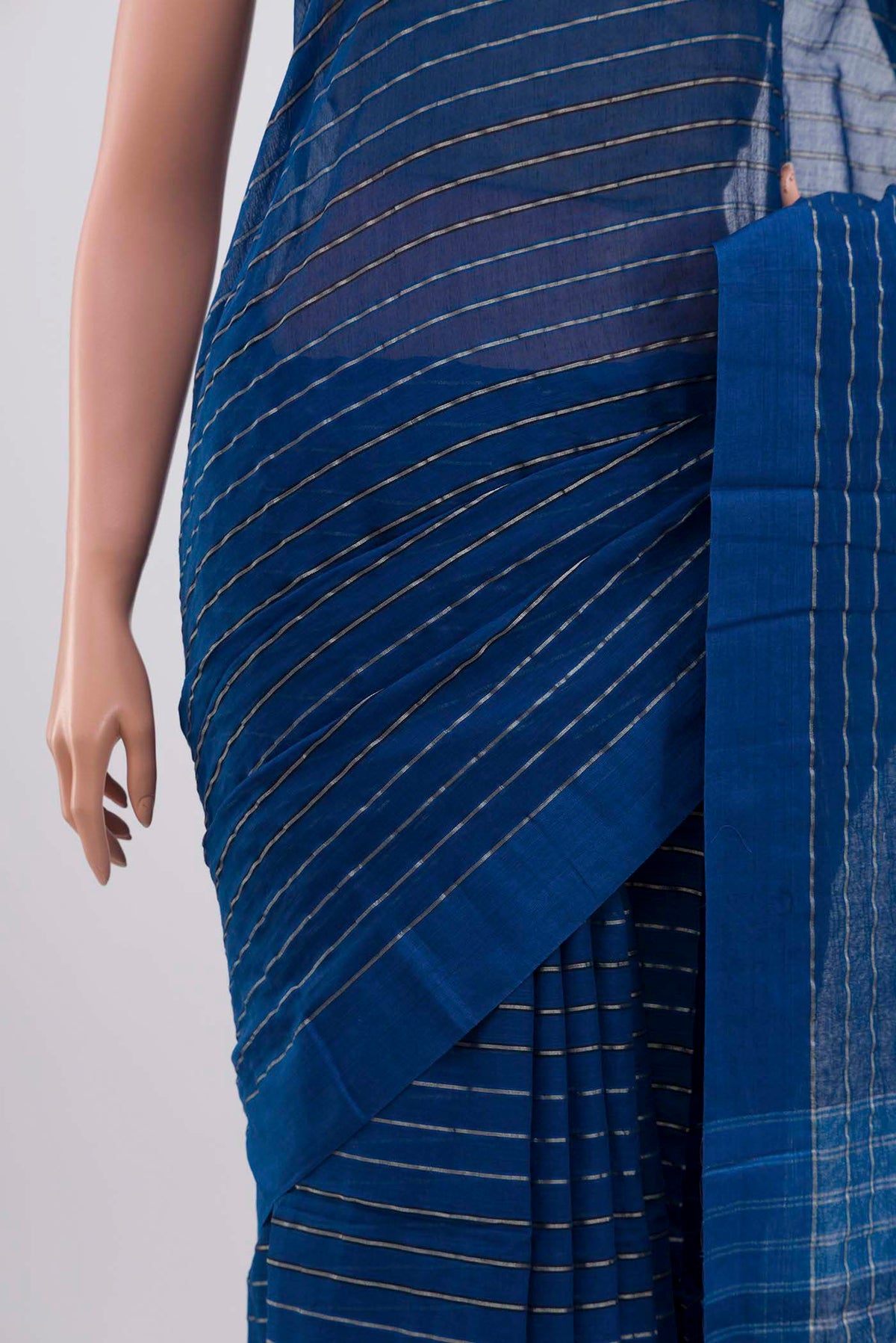 Border image of Mishri, a celebration of summer in Bengal cotton, is woven in fine 60-count cotton and drapes with natural comfort Soft stripes move in gentle linear patterns across the fabric, creating a lively yet balanced design The fine checks they form are a gentle reminder of crystal sugar, lending the saree its name Light, breathable, and effortlessly wearable for sunlit days