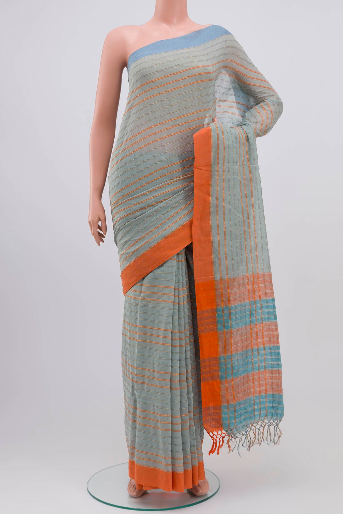 Mishri, a celebration of summer in Bengal cotton, is woven in fine 60-count cotton and drapes with natural comfort Soft stripes move in gentle linear patterns across the fabric, creating a lively yet balanced design The fine checks they form are a gentle reminder of crystal sugar, lending the saree its name Light, breathable, and effortlessly wearable for sunlit days displayed on a mannequin