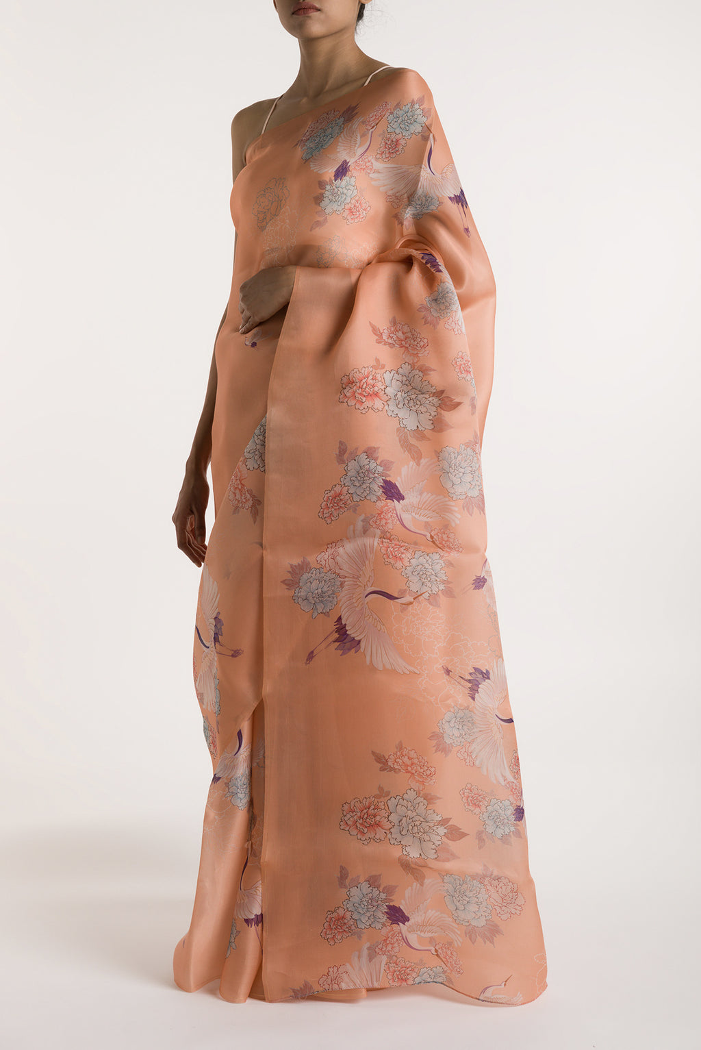 Close up image of the blouse of Our 'Flying Cranes' printed on a satin organza saree is crafted in a peach tone that features hand-illustrated tropical prints of flying cranes in the endless sky. The saree is finished with an intricately detailed thin Zari line along the border.
