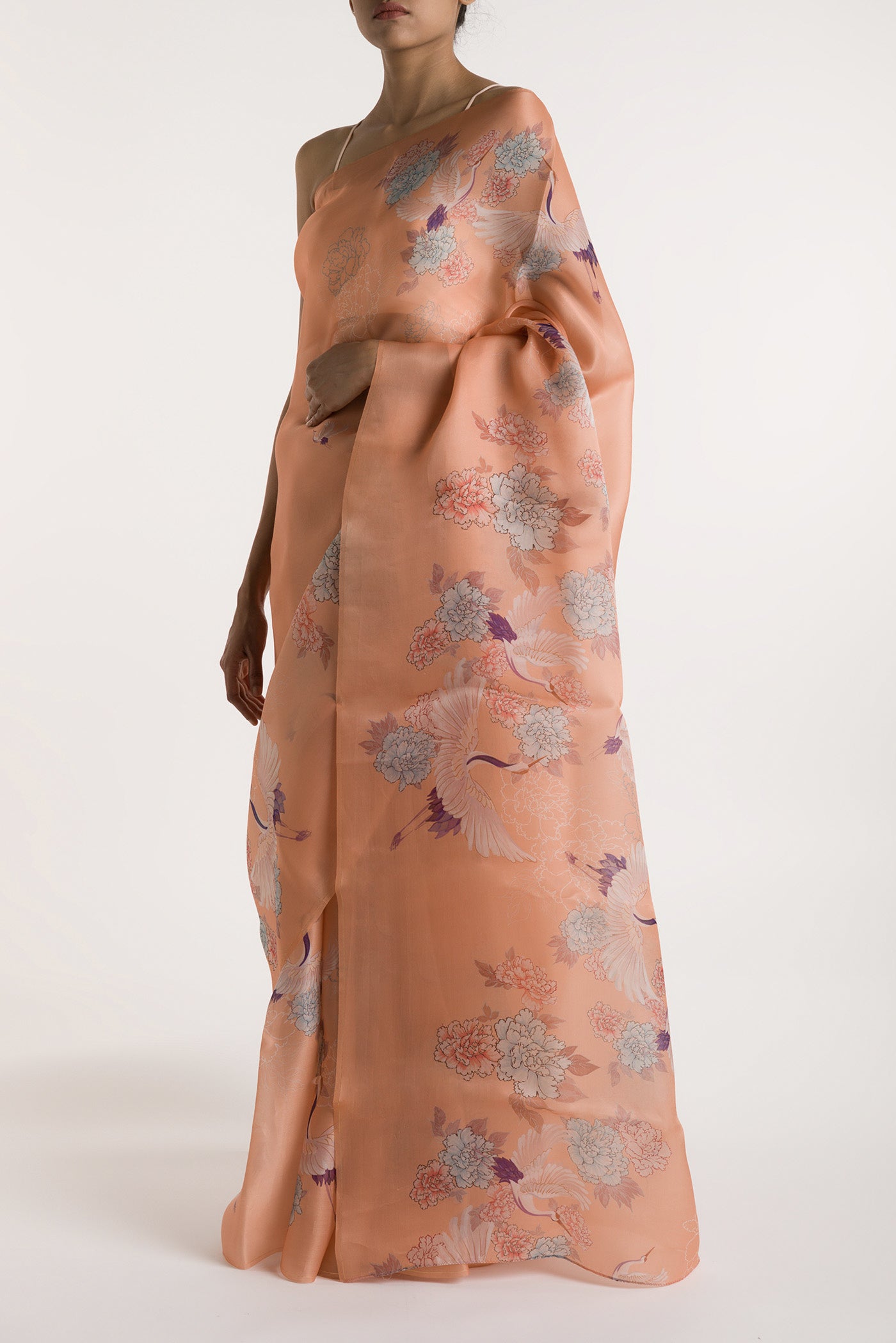 Close up image of the blouse of Our 'Flying Cranes' printed on a satin organza saree is crafted in a peach tone that features hand-illustrated tropical prints of flying cranes in the endless sky. The saree is finished with an intricately detailed thin Zari line along the border.