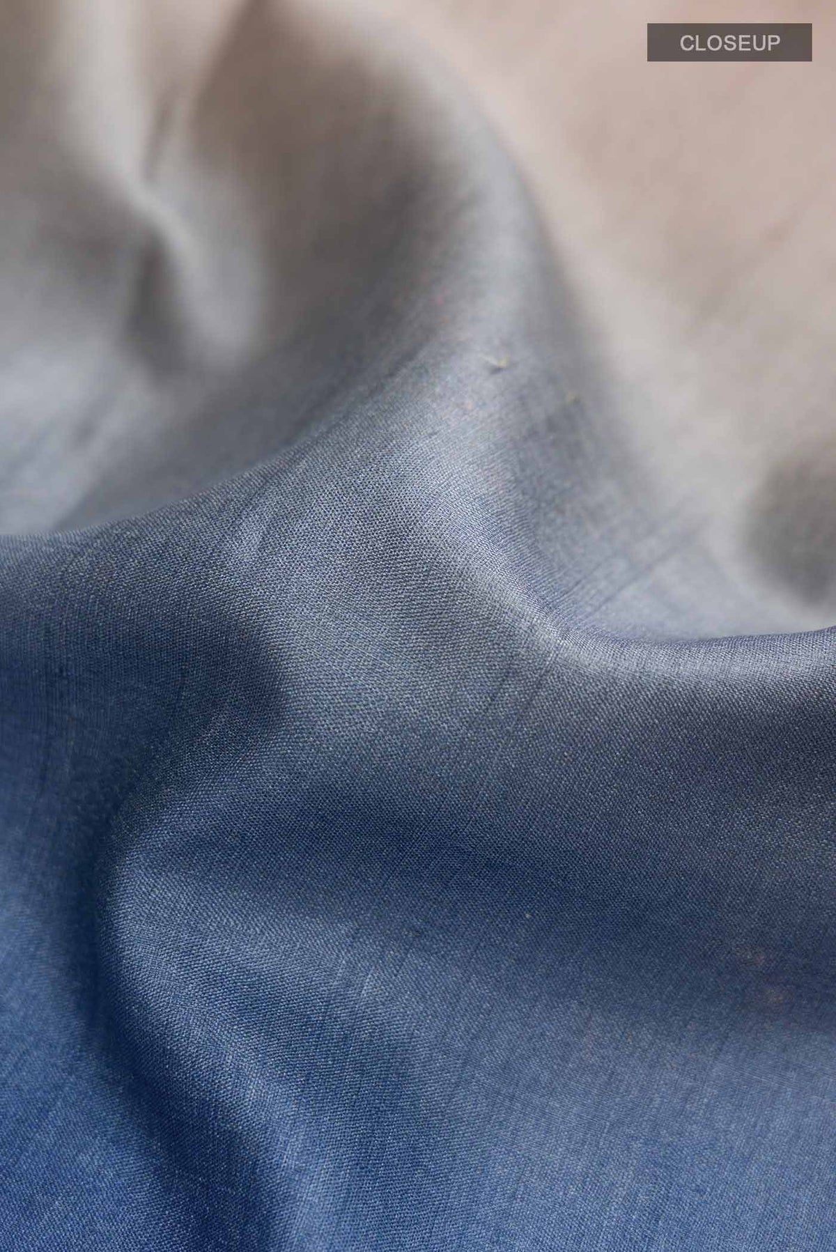 Close up of Blue Tussar Silk Saree With Printed design on the body and Plain Border displaying folds