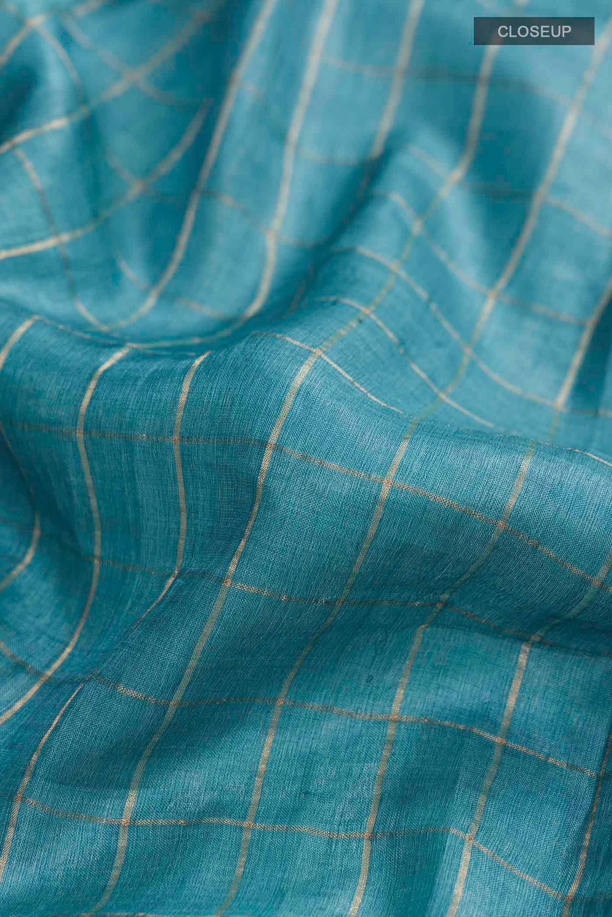 Close up of Blue Tussar Silk Saree with Printed design on the body and Zari Border displaying folds