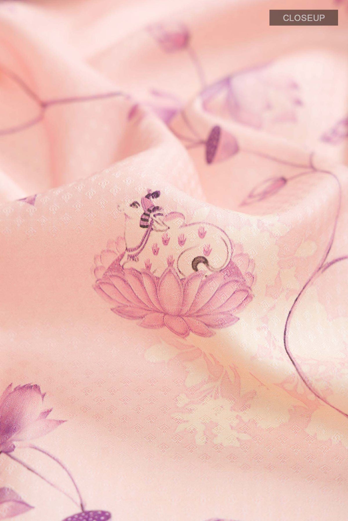 Close up of Pink Printed Silk Saree With Printed design on the body and Zari Border displaying folds
