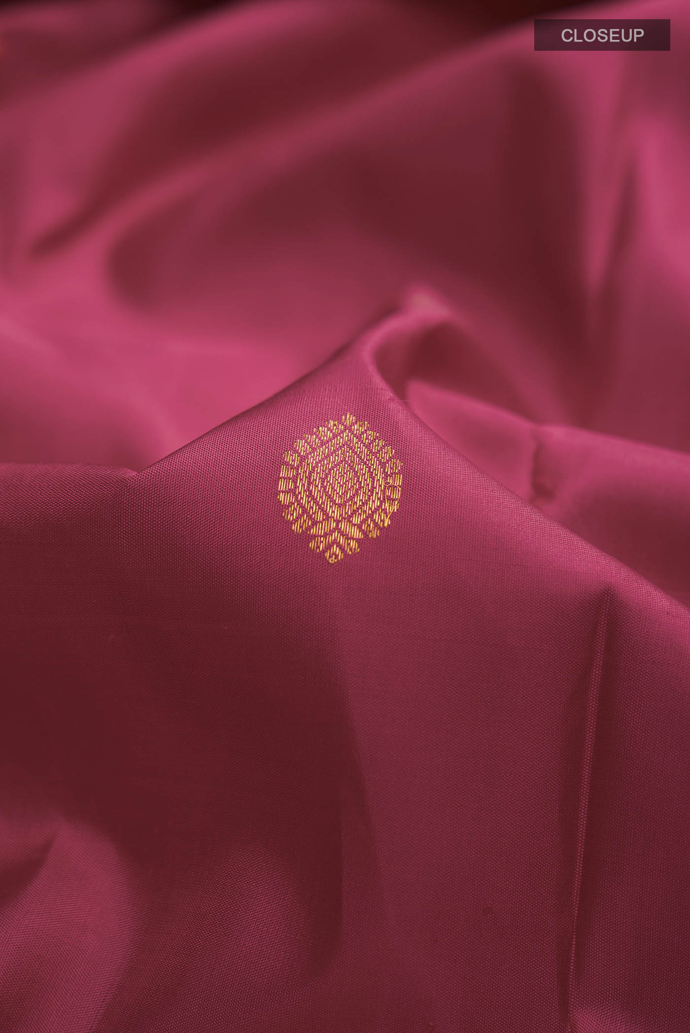 Close up of Magenta Kanchipuram Silk Saree with Zari Butta on the body and Zari Border displaying folds