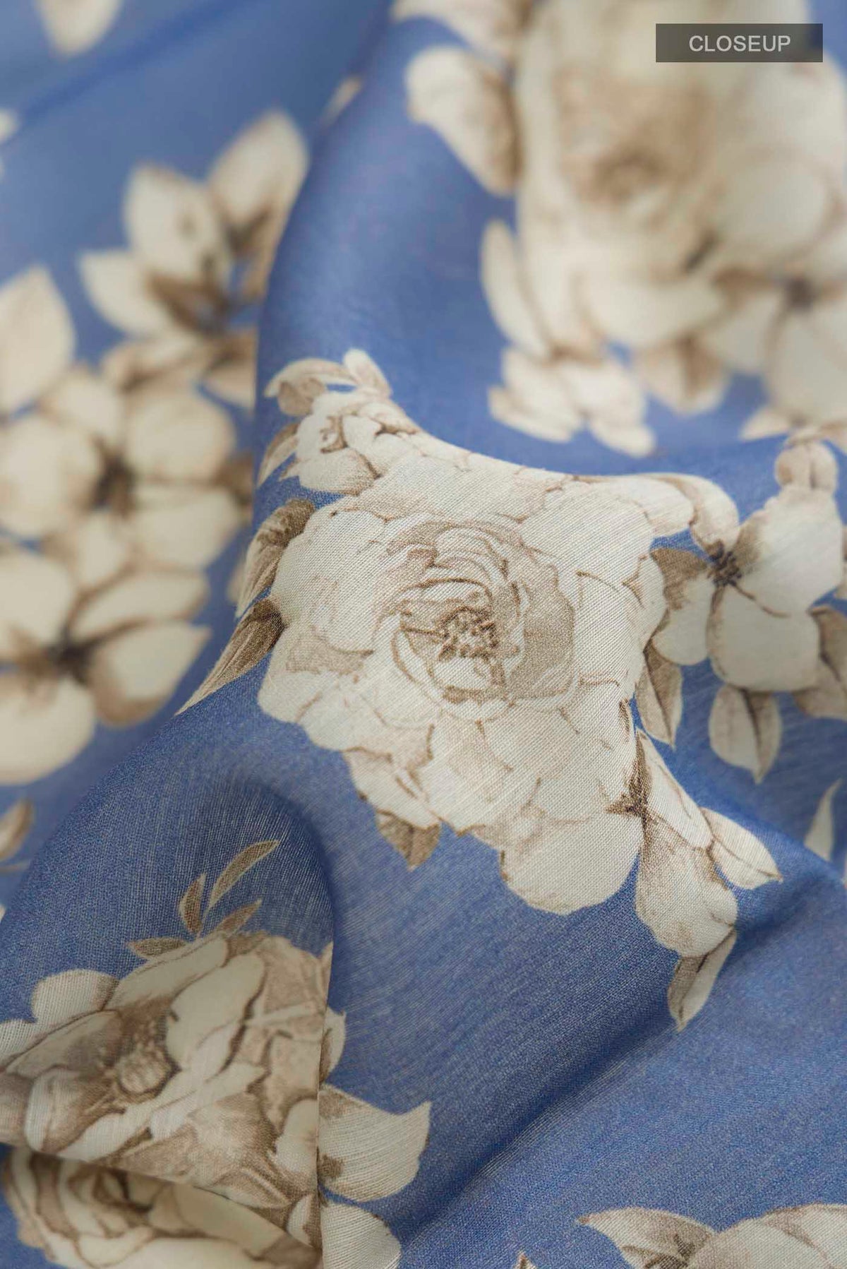 Close up of Blue Tussar Silk Saree with Printed design on the body and Embroidery Border displaying folds