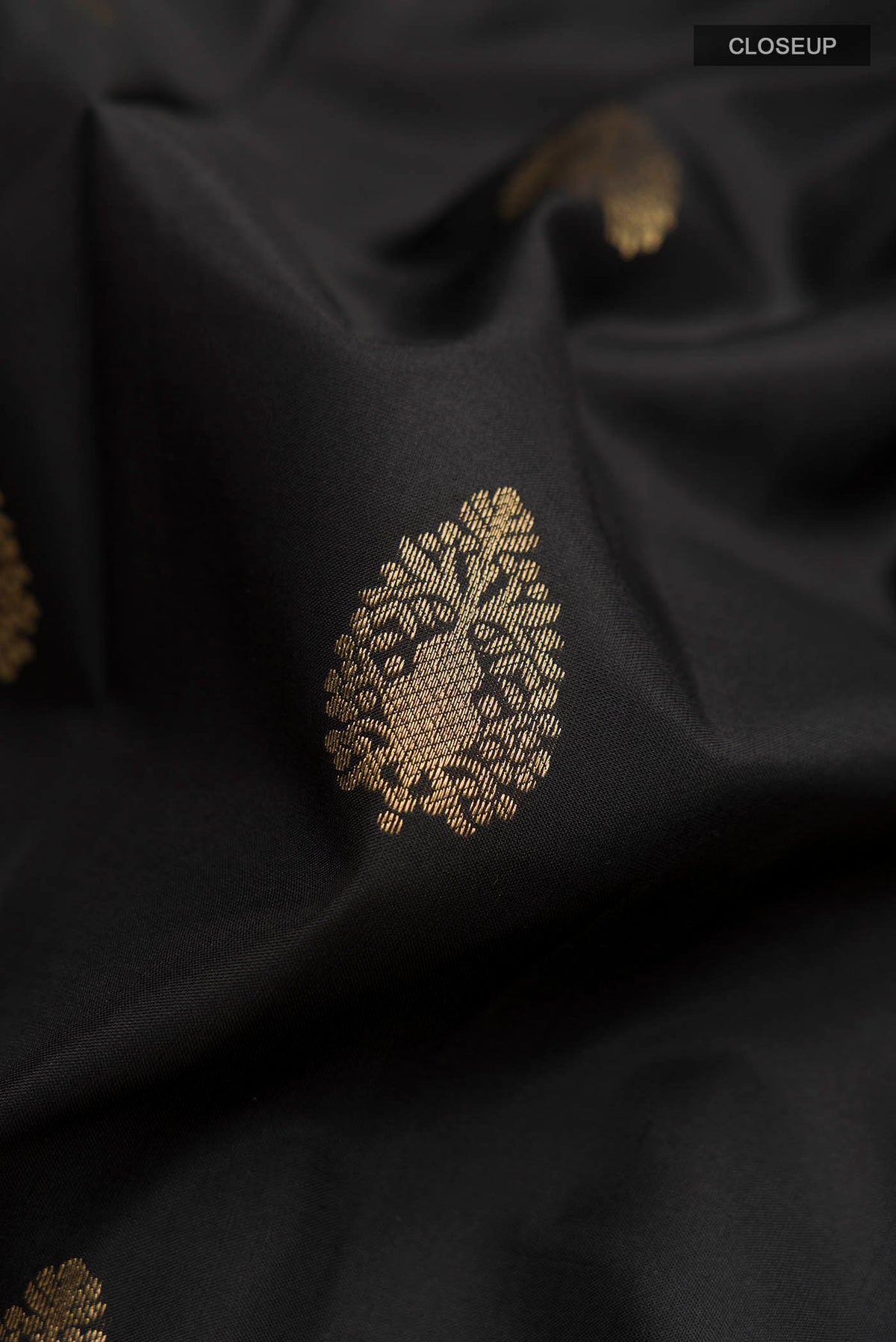 Close up of Black Kanchipuram Silk Saree with Zari Butta on the body and Zari Border displaying folds
