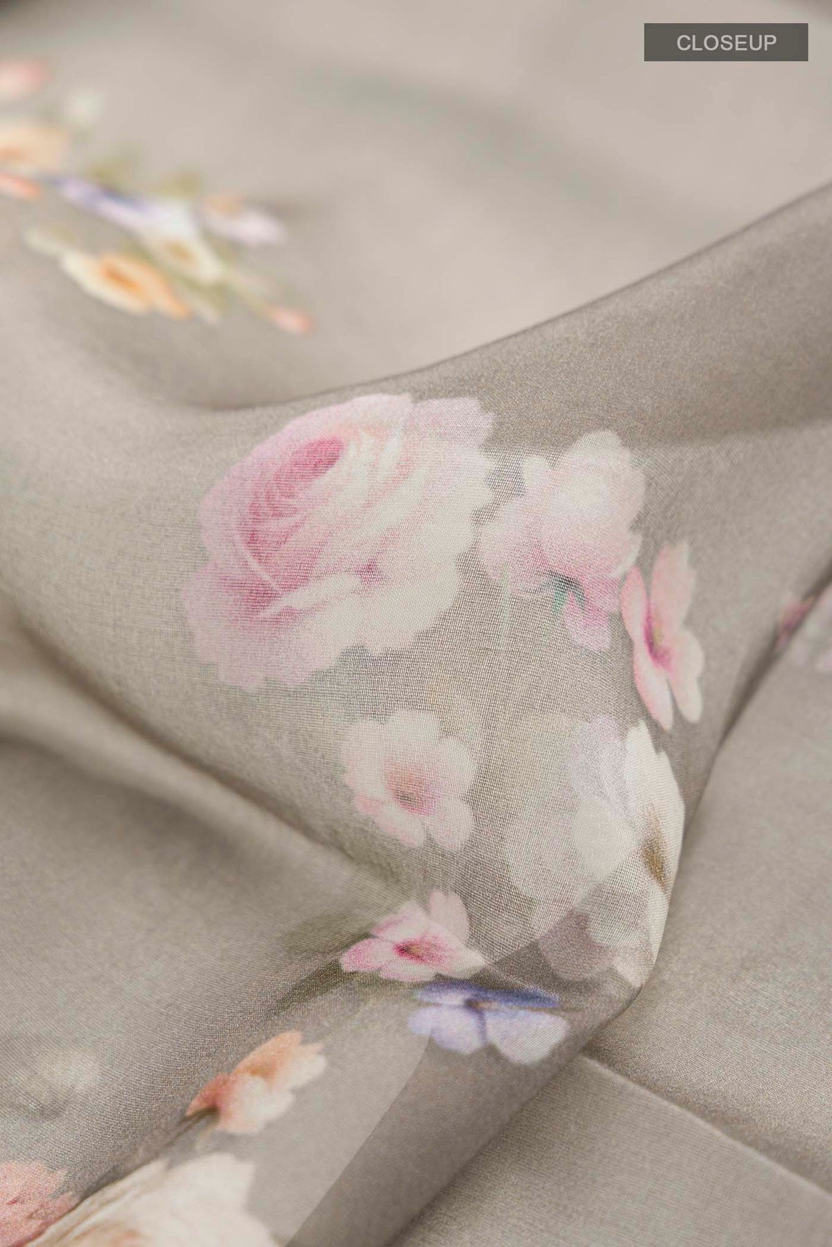 Close up of Grey Organza Silk Saree with Printed design on the body and Zari Border displaying folds