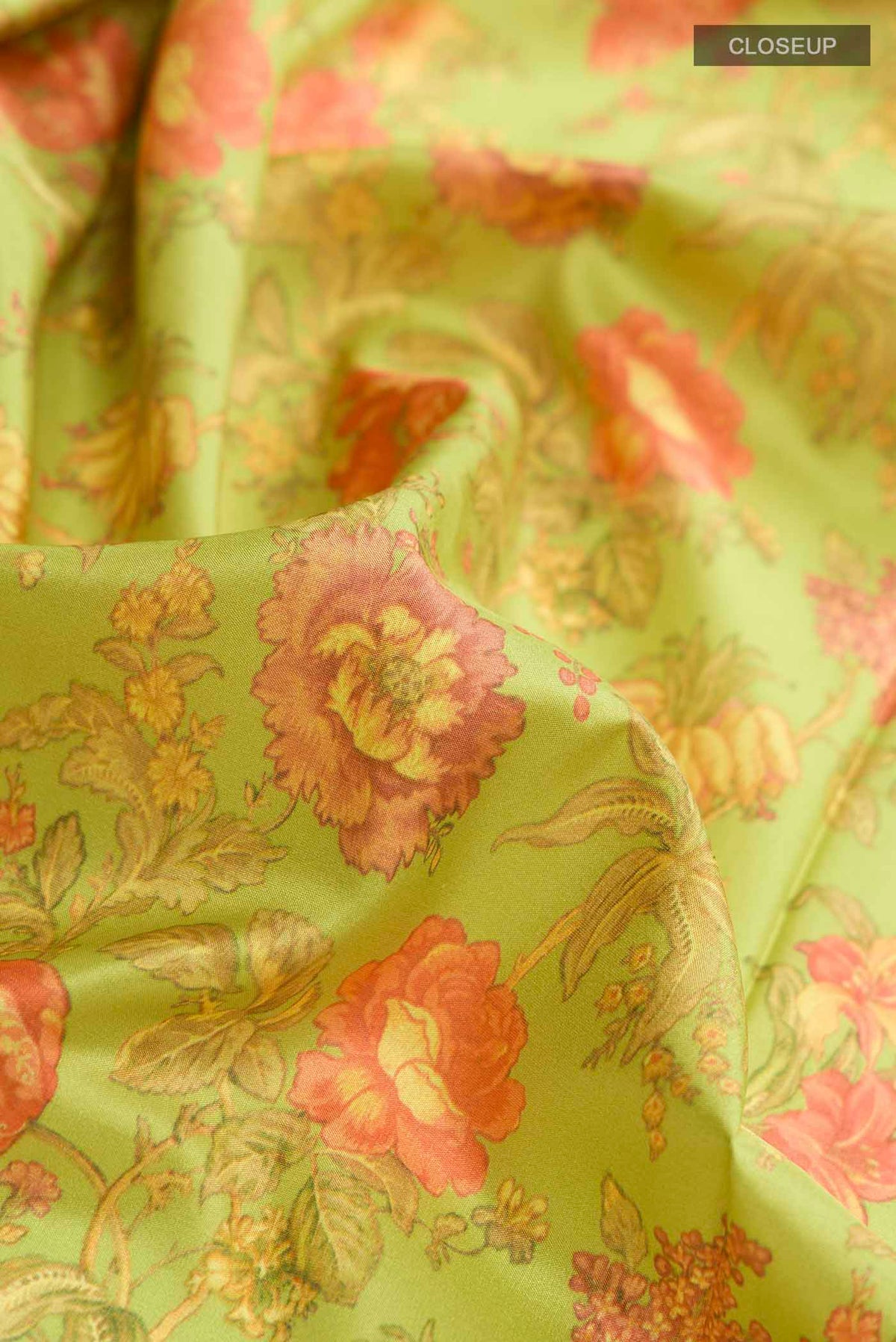 Close up of Green Printed Silk Saree with Floral Print on the body and Zari Border displaying folds