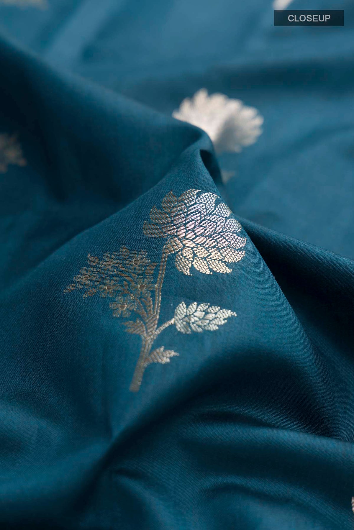 Close up of Blue Banarasi Raw Silk Saree with Zari Butta on the body and Zari Border displaying folds