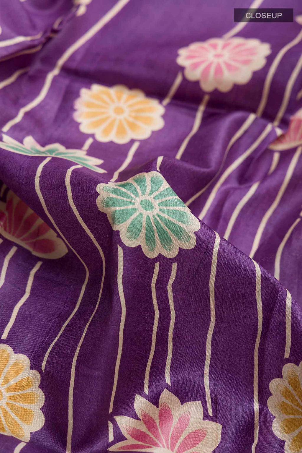 Close up of Violet Tussar Silk Saree with Printed design on the body and Zari Border displaying folds