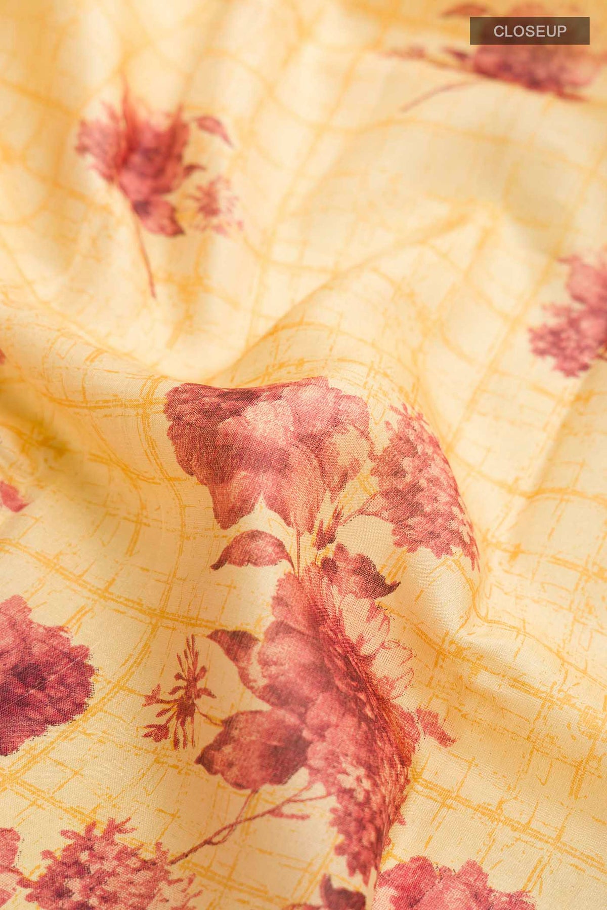 Close up of Mustard Tussar Silk Saree with Printed design on the body and Zari Border displaying folds