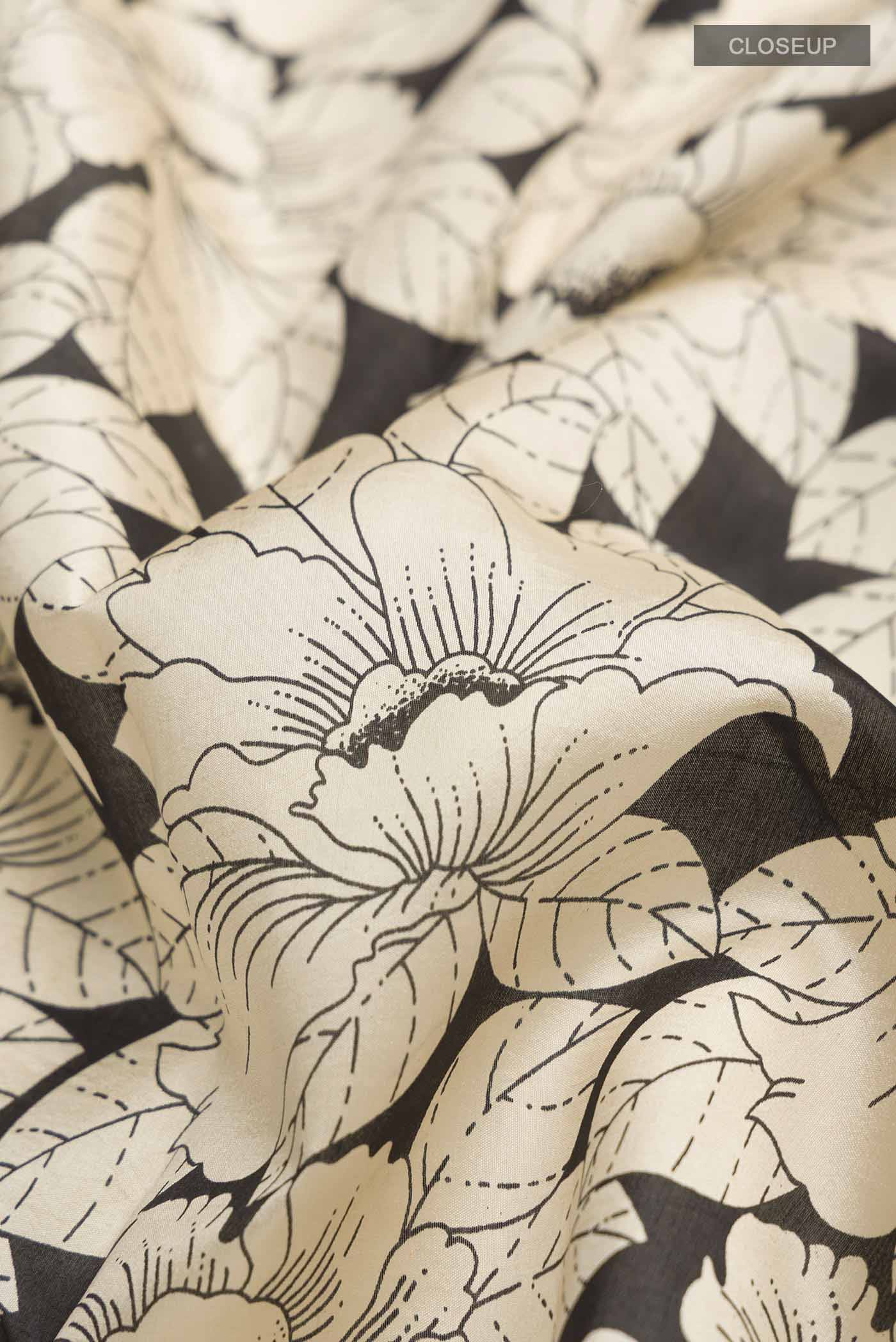 Close up of Cream Printed Silk Saree with Printed design on the body and Plain Border displaying folds