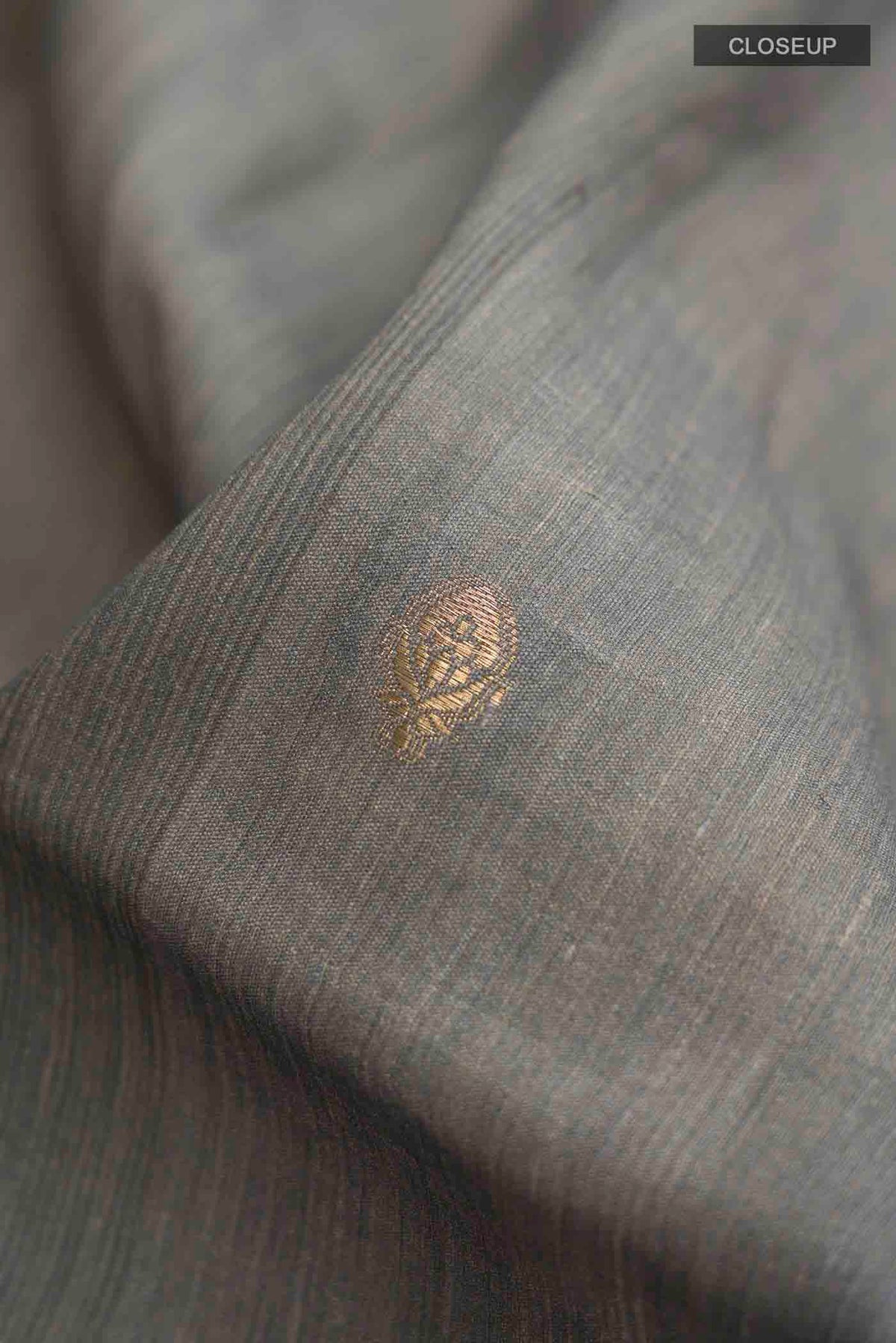 Close up of Grey Tussar Silk Saree with Zari Butta on the body and Printed Border displaying folds