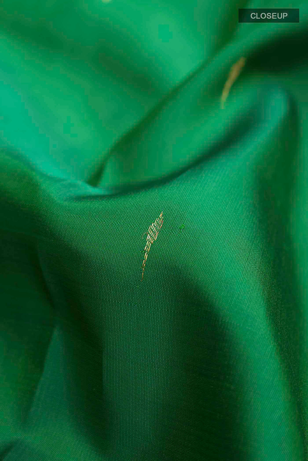Close up of Green Kanchipuram Silk Saree with Zari Butta on the body and Zari Border displaying folds