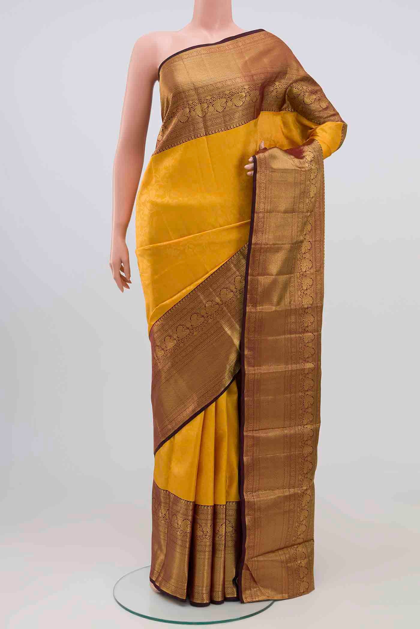 Mustard Kanchipuram Silk Saree with Zari Brocade on the body and Zari Border.  displayed on a mannequin