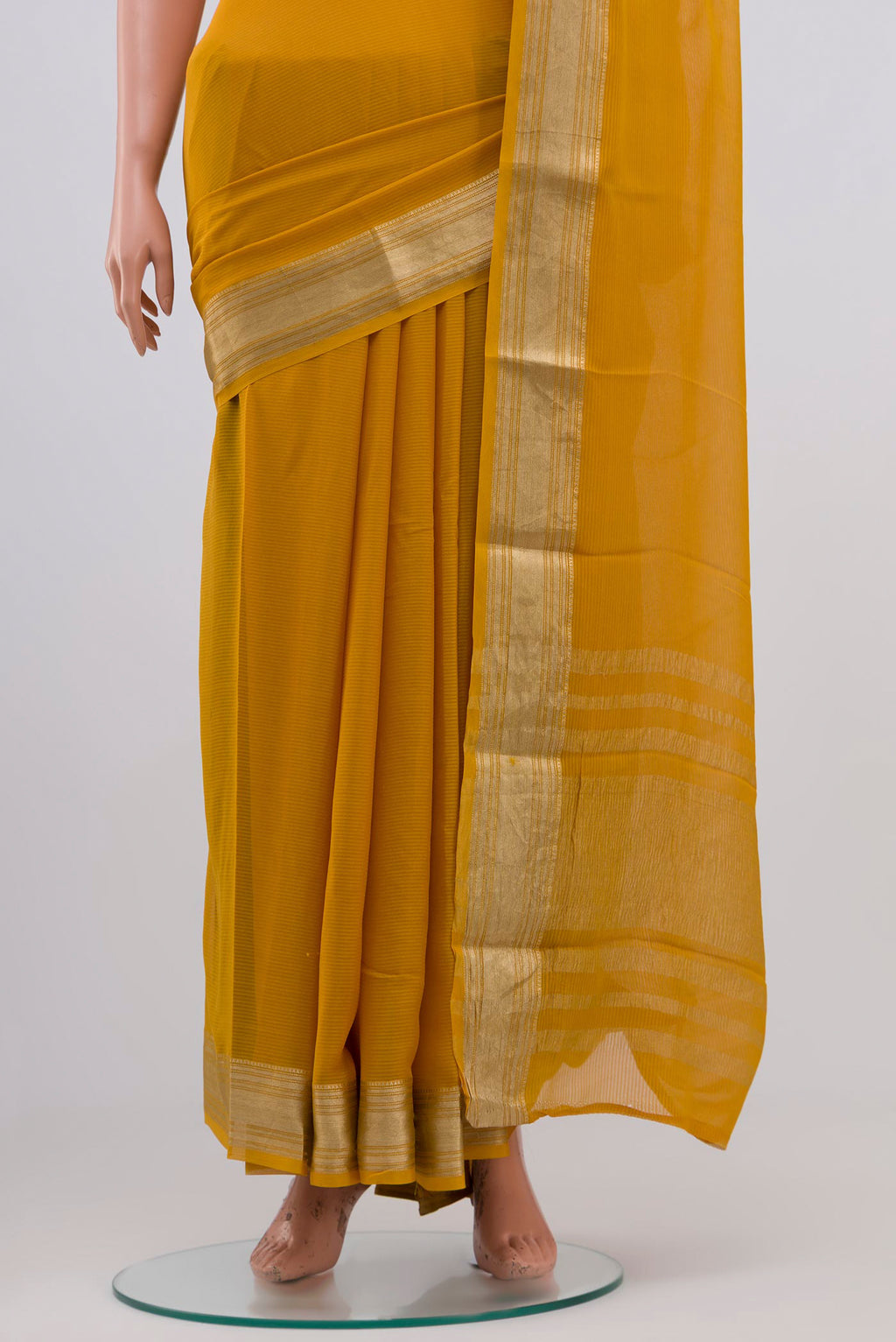 Pleats and pallu of Mustard Georgette Saree with Zari Butta on the body and Zari Border. 