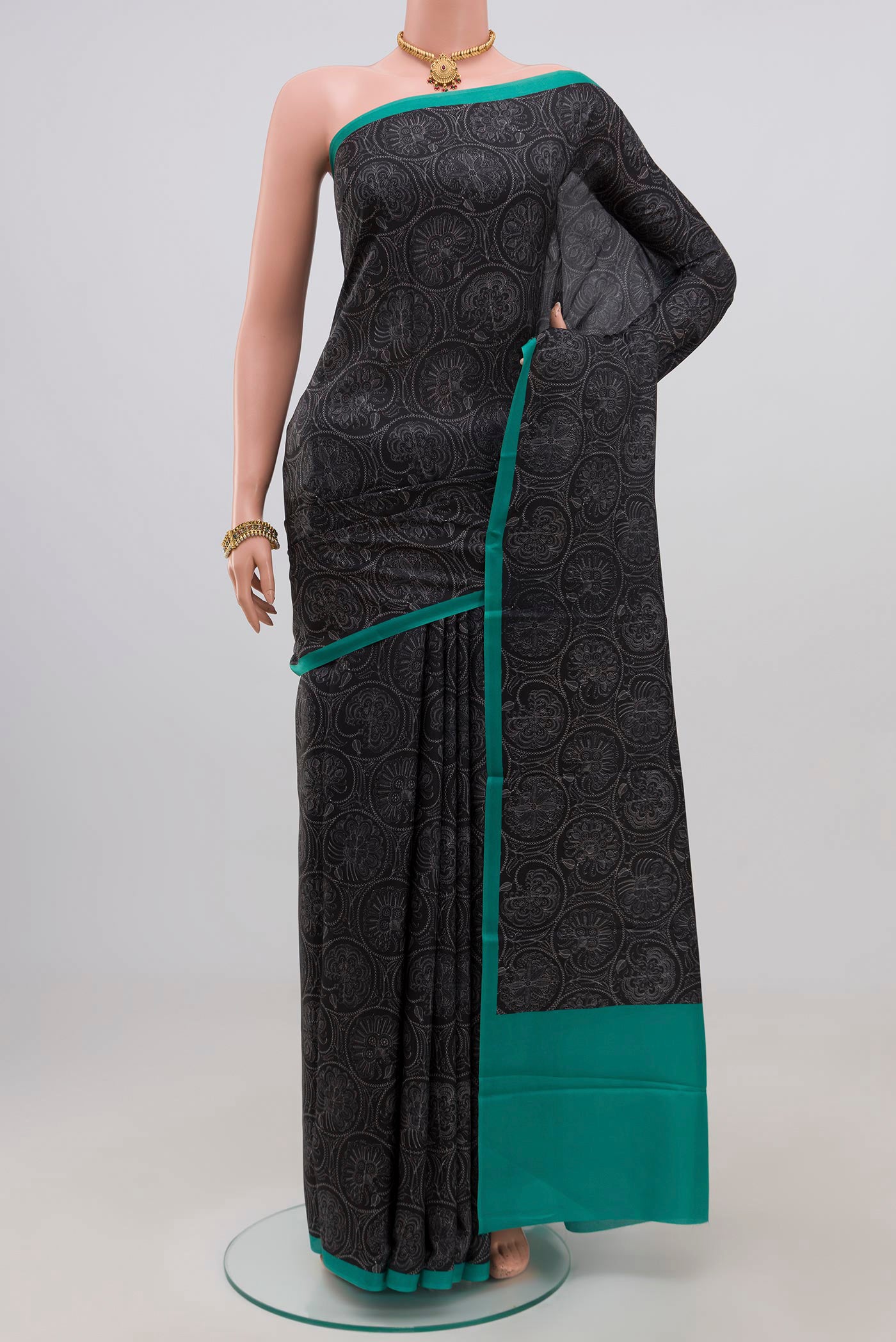 Black Printed Silk Saree with Printed design on the body and Plain Border.  displayed on a mannequin
