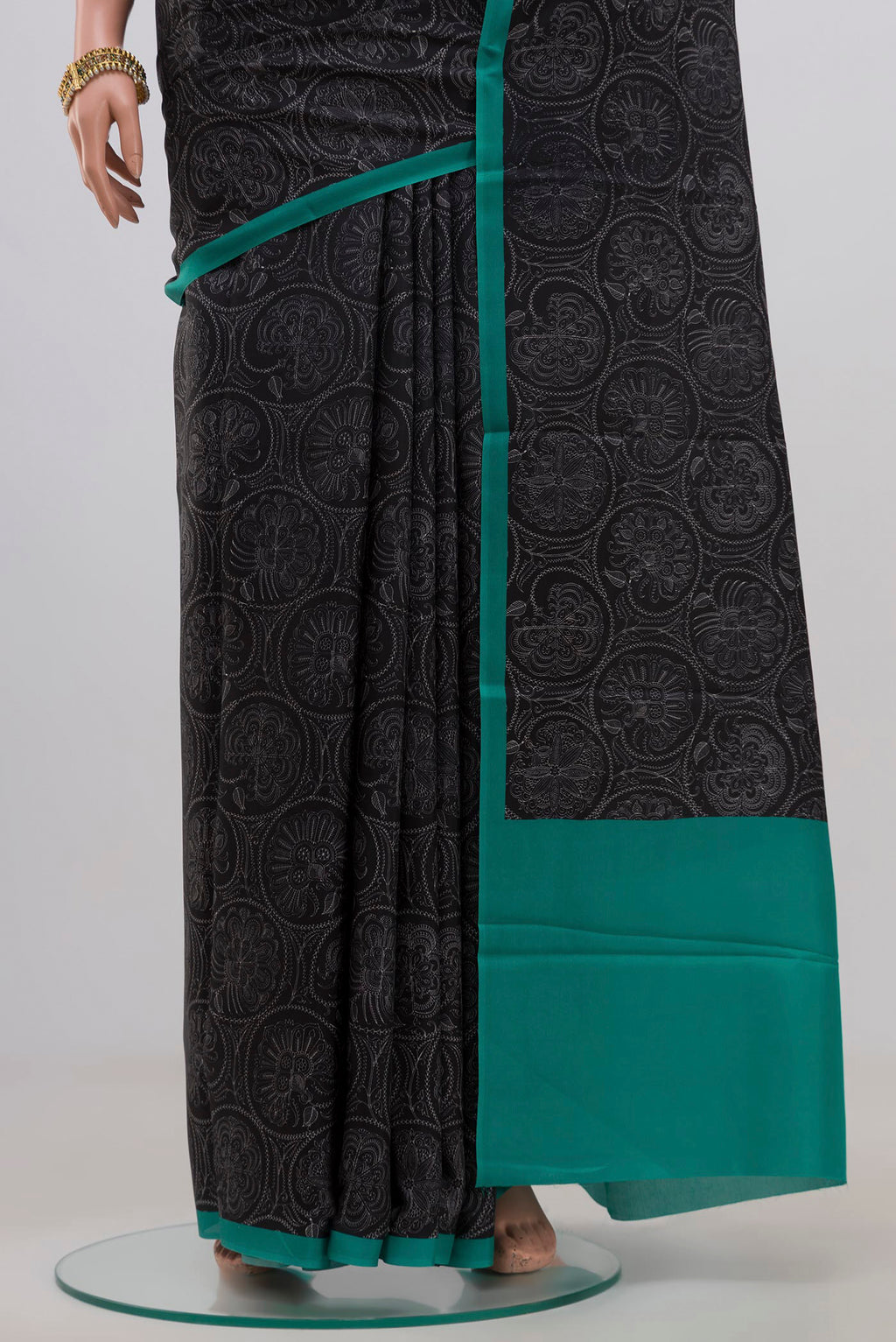 Pleats and pallu of Black Printed Silk Saree with Printed design on the body and Plain Border. 