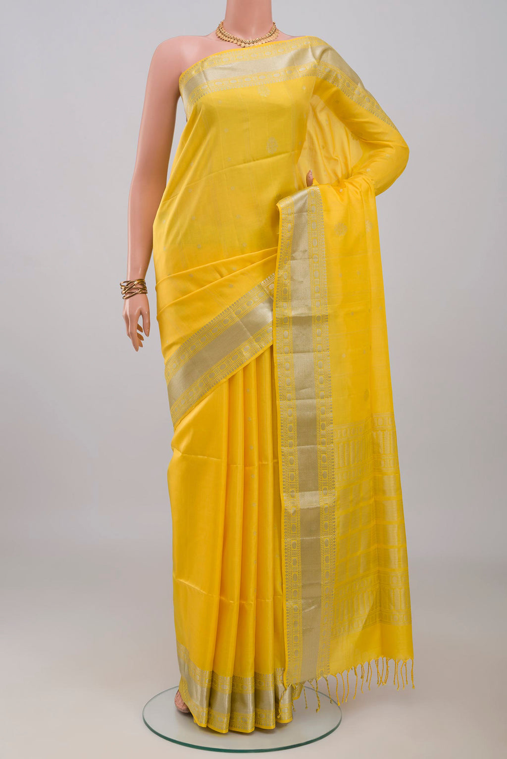 Yellow Soft Silk Saree with Zari Butta on the body and Zari Border.  displayed on a mannequin