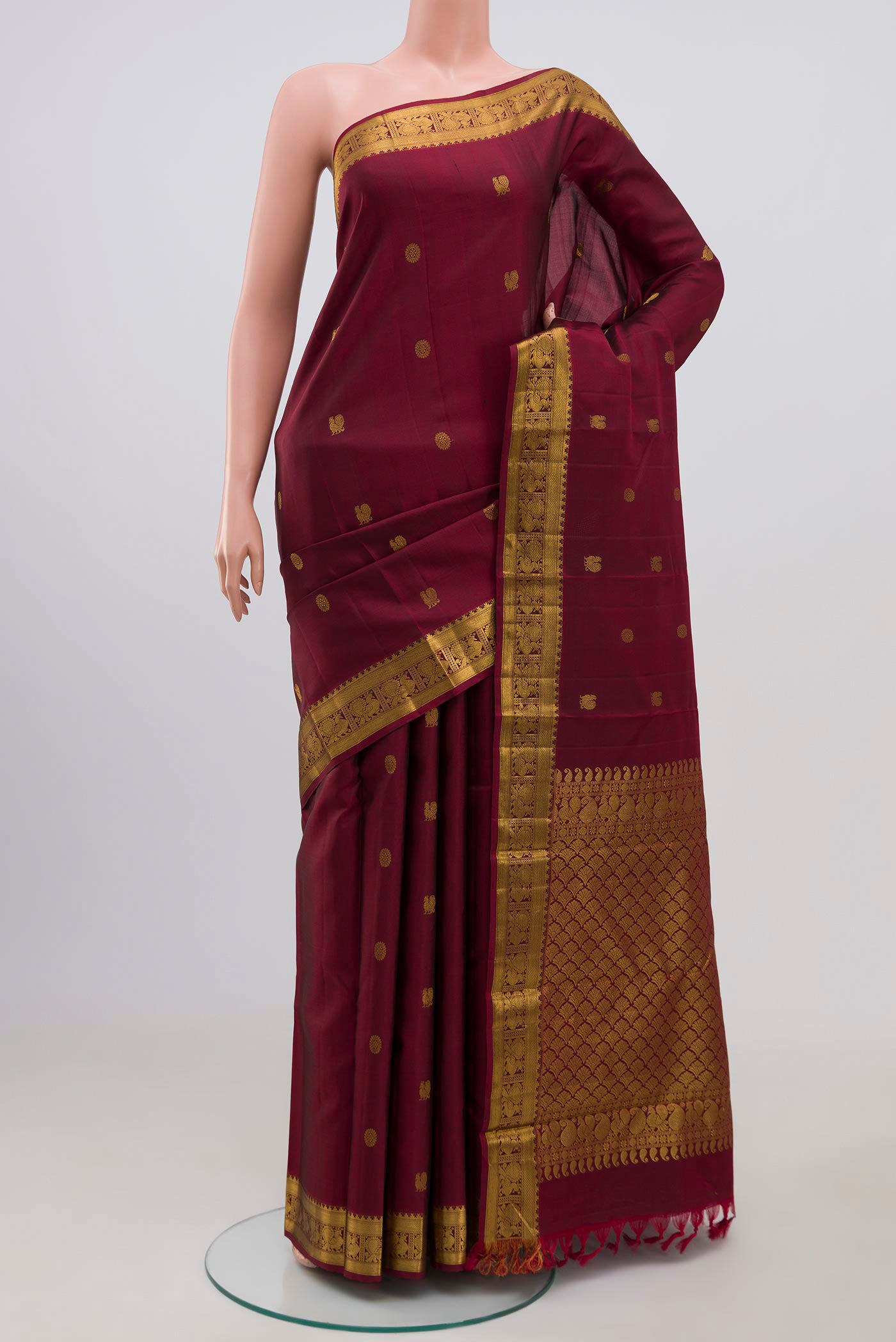 Maroon Kanjivaram Silk Saree with Zari Butta on the body and Zari Border.  displayed on a mannequin