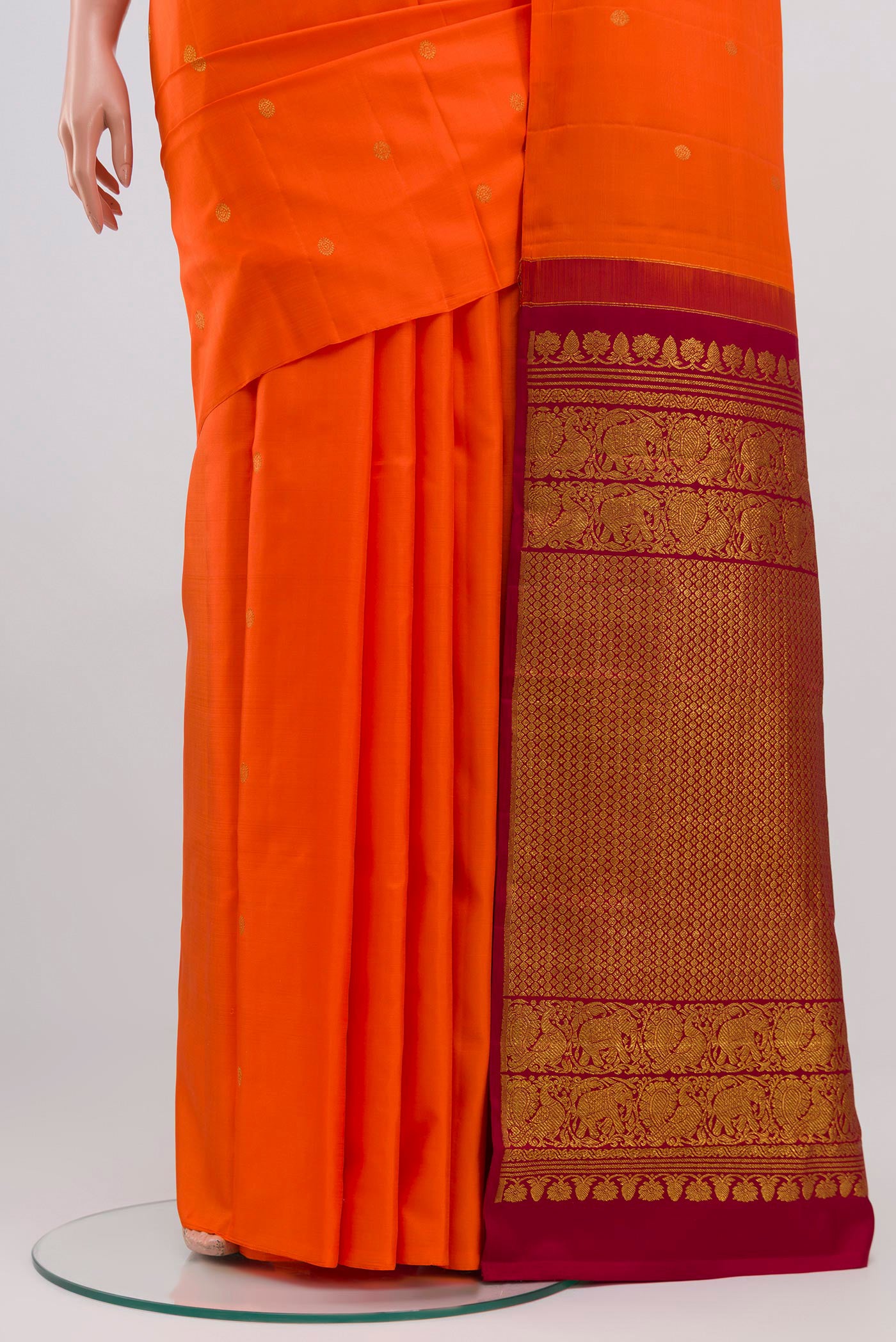 Pleats and pallu of Orange Kanchipuram Saree with Zari Butta on the body and Without Border. 
