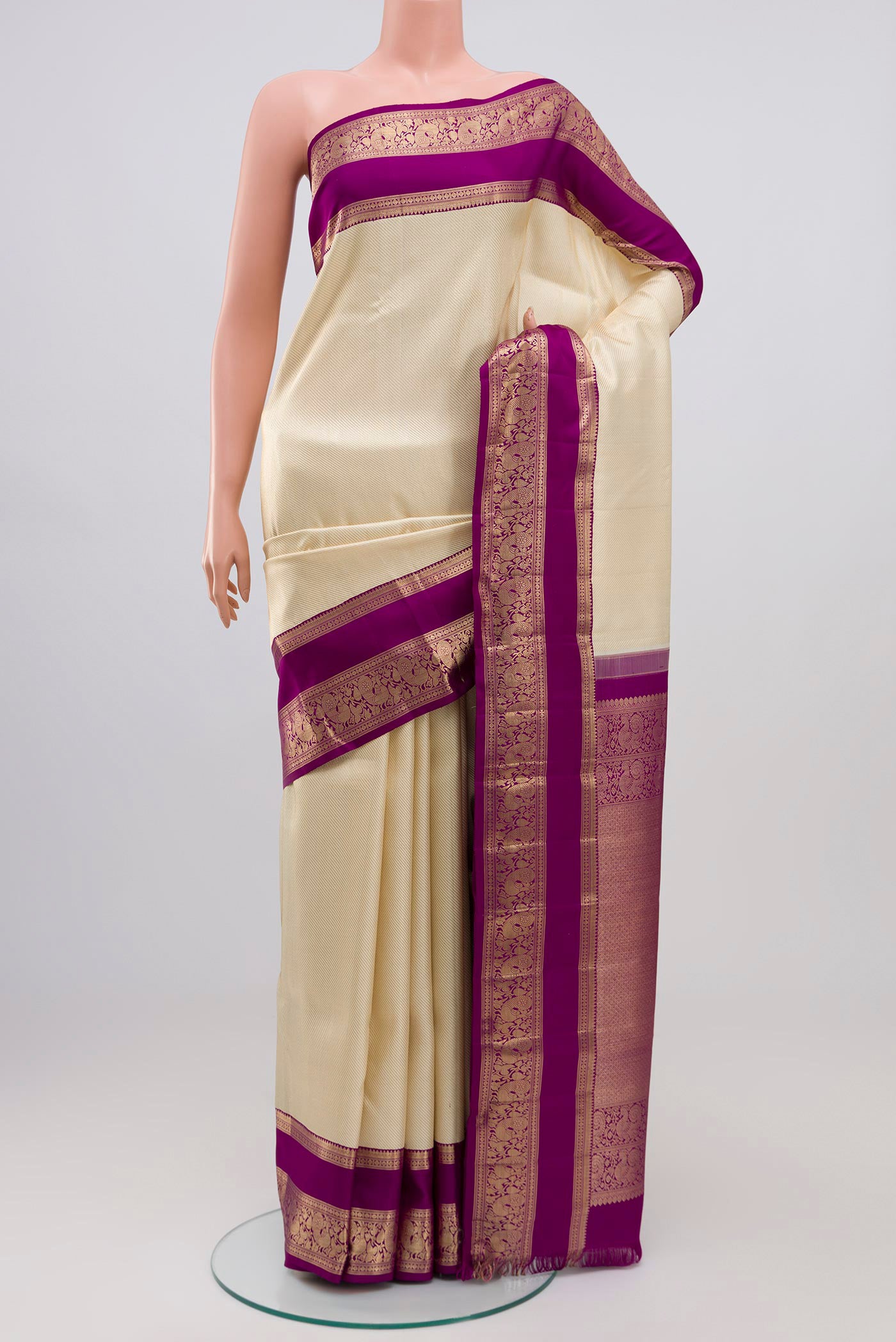 Cream Kanchipuram Silk Saree with Zari Brocade on the body and Zari Border.  displayed on a mannequin