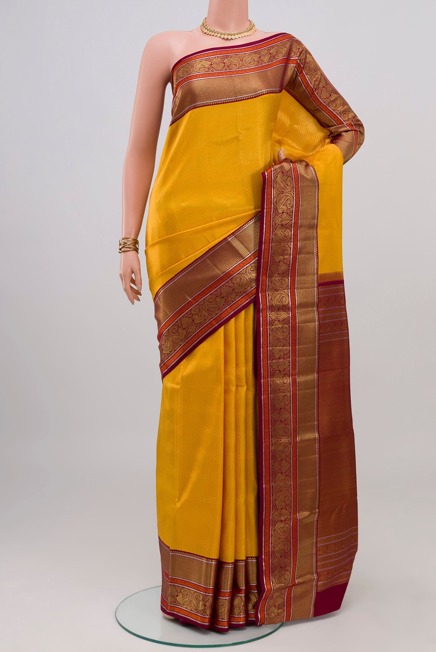 Yellow Kanchipuram Silk Saree with Zari Brocade on the body and Zari Border.  displayed on a mannequin