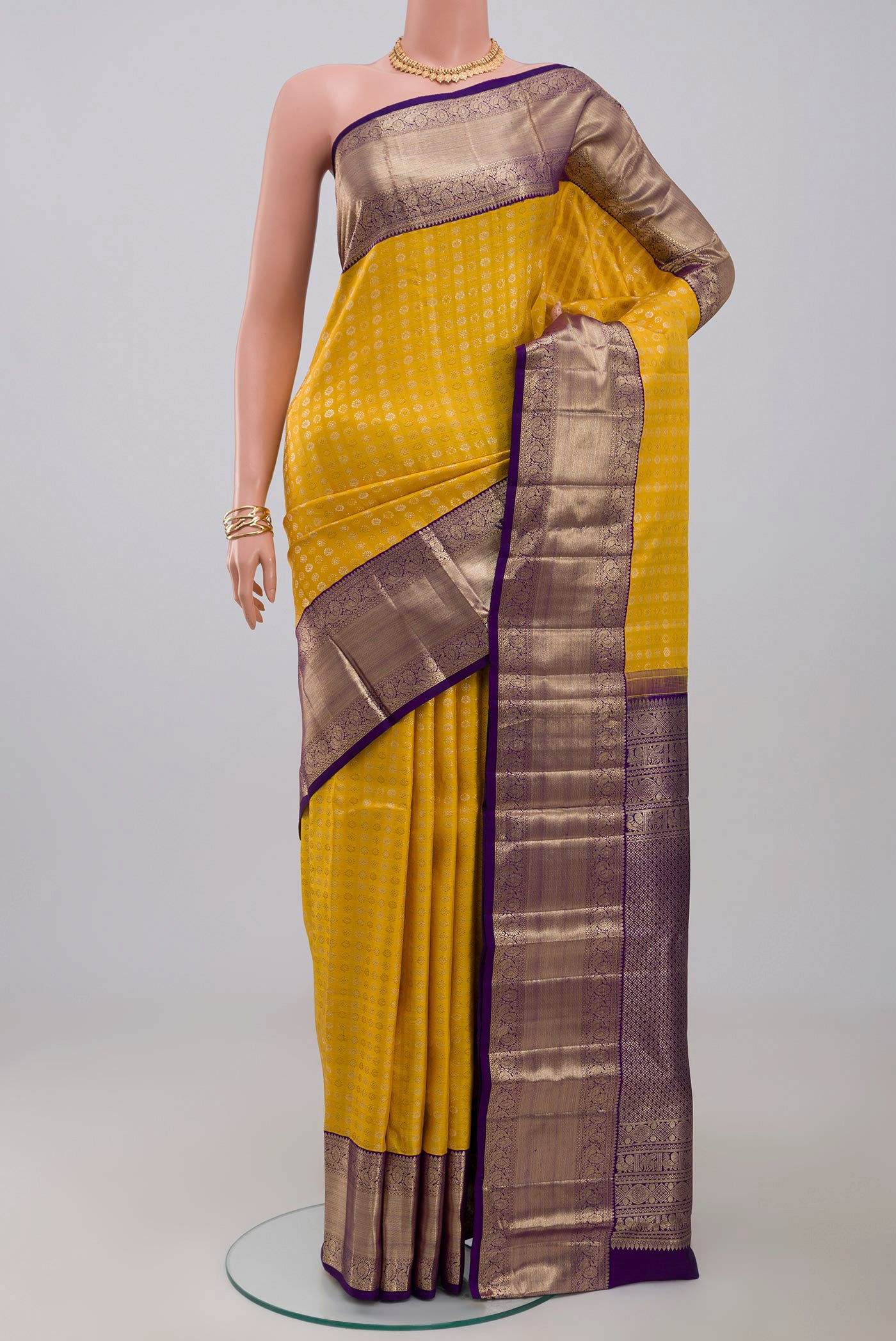 Yellow Kanchipuram Silk Saree with Zari Butta on the body and Zari Border.  displayed on a mannequin