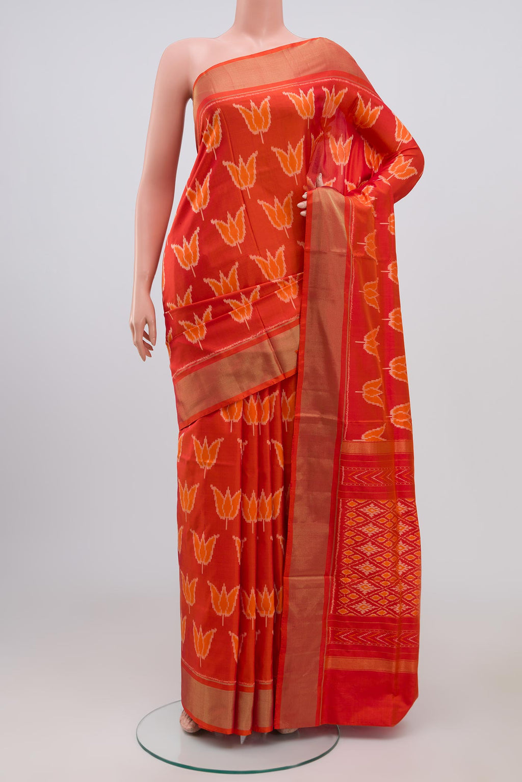 Orange Pochampally Silk Saree with Ikat design on the body and Zari Border.  displayed on a mannequin