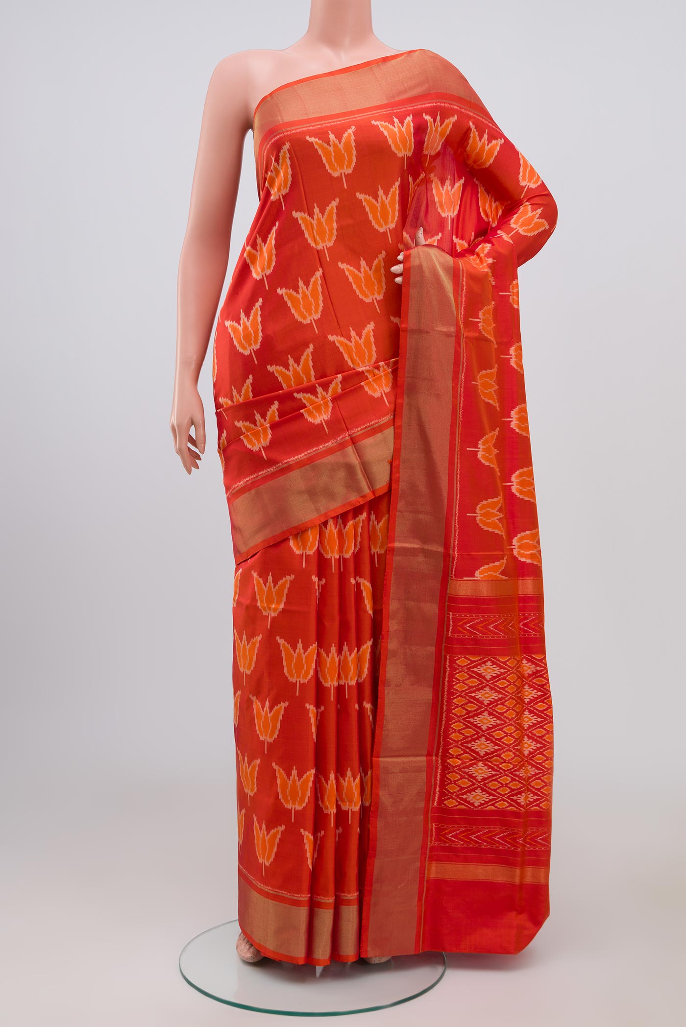 Orange Pochampally Silk Saree with Ikat design on the body and Zari Border.  displayed on a mannequin
